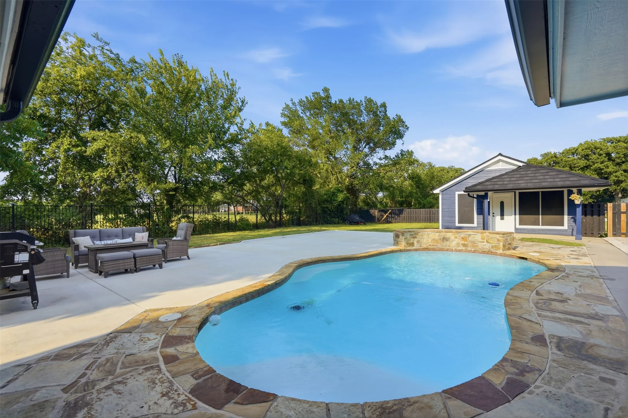 Custom-shaped swimming pool with flagstone coping and a stone-clad raised feature