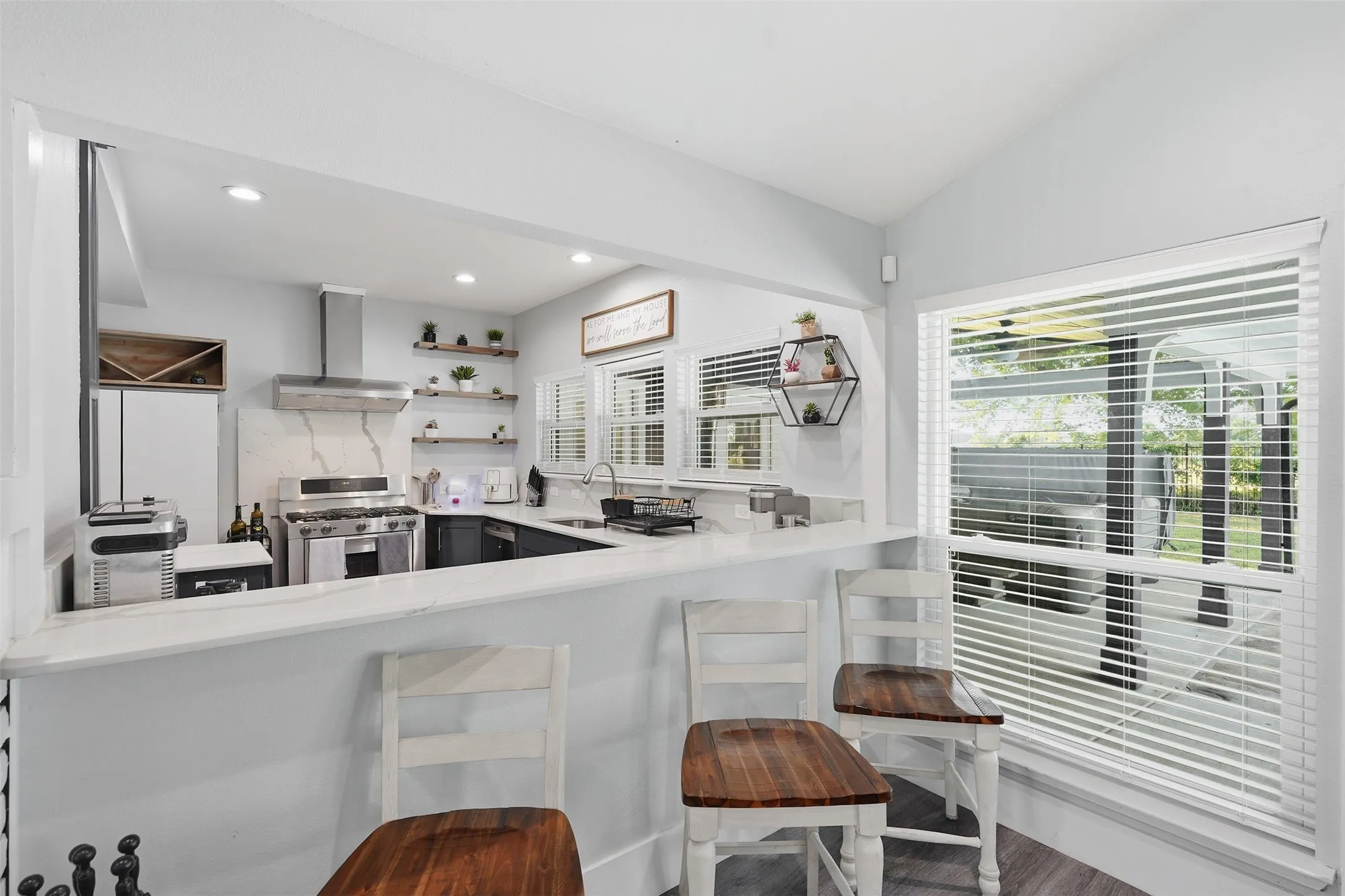 Kitchen featuring a pass-through counter, white countertops, stainless steel appliances, and open shelving