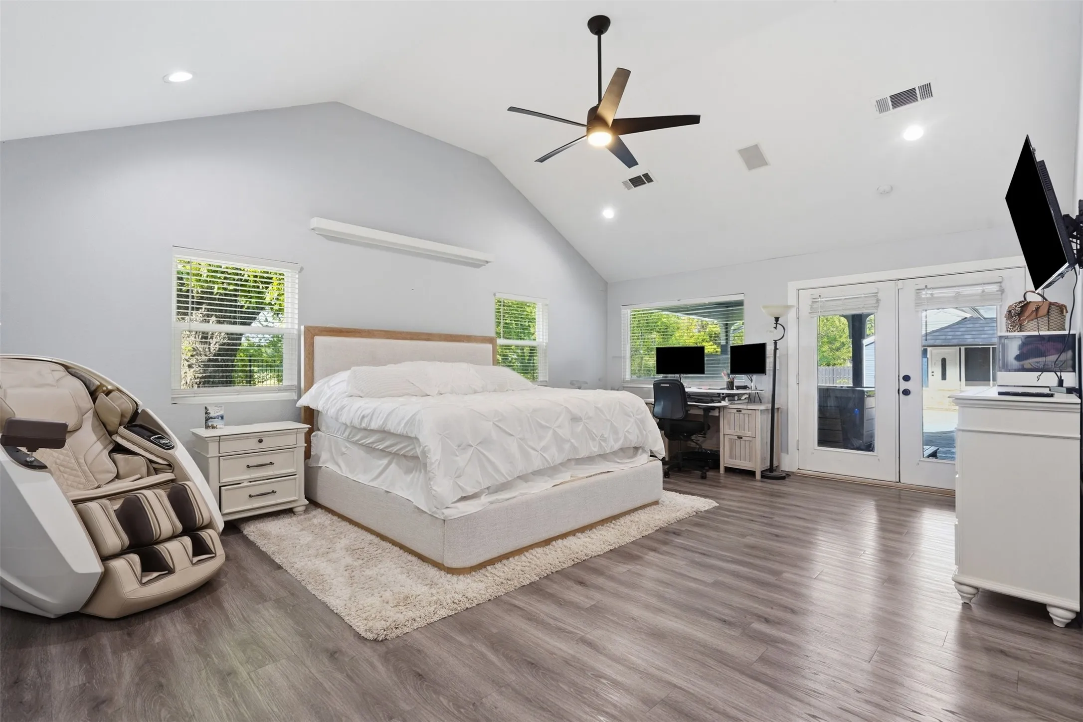 Spacious room featuring vaulted ceilings, wood-finish flooring, recessed lighting, and a contemporary ceiling fan