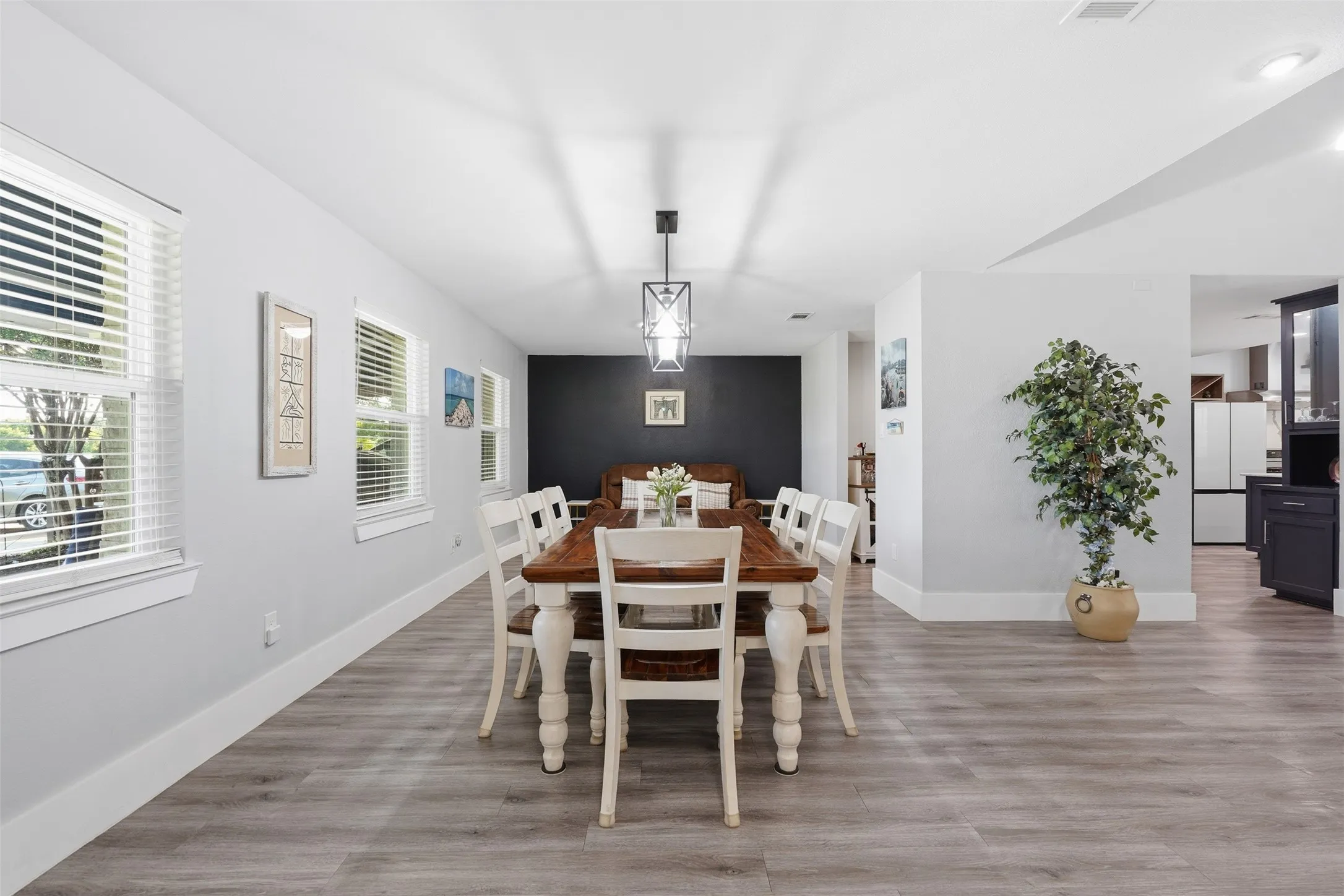 Open-concept dining area featuring wood-finish flooring, recessed lighting, and a modern chandelier