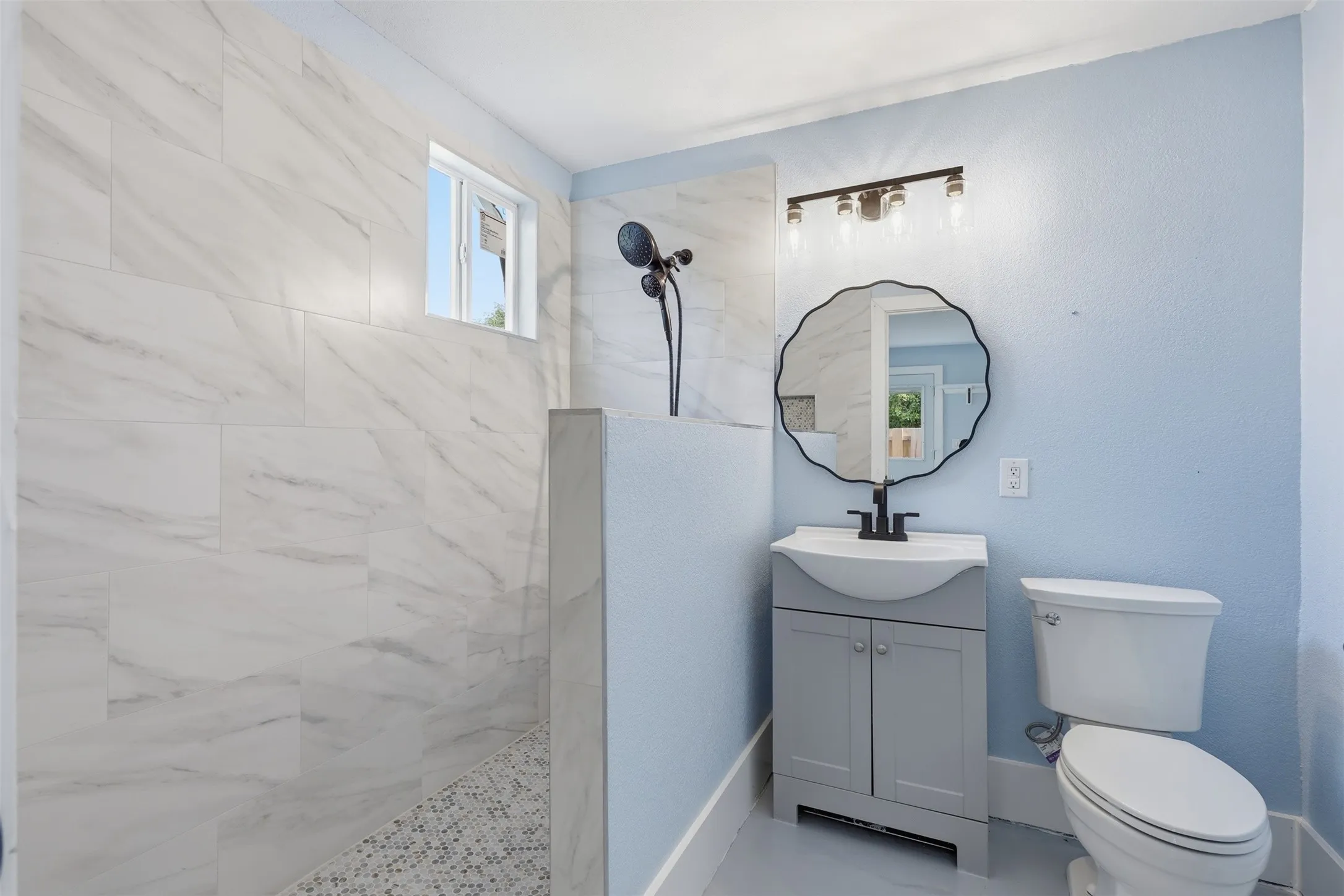 Modern bathroom featuring a walk-in shower with large format tile walls and a mosaic tile floor