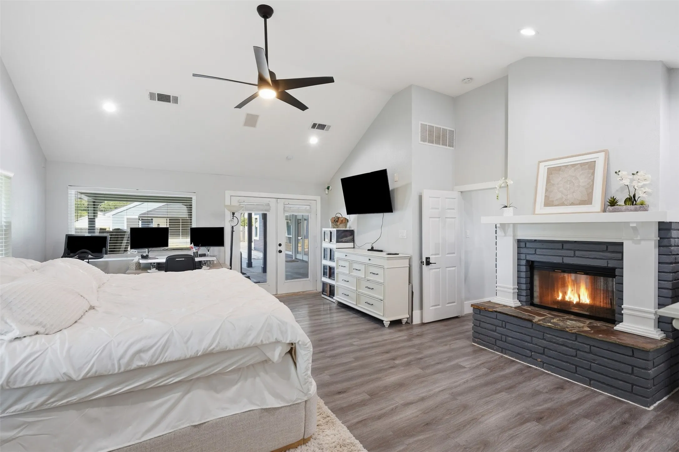 Wood-finish flooring throughout this room featuring a painted brick fireplace with a white mantel and hearth