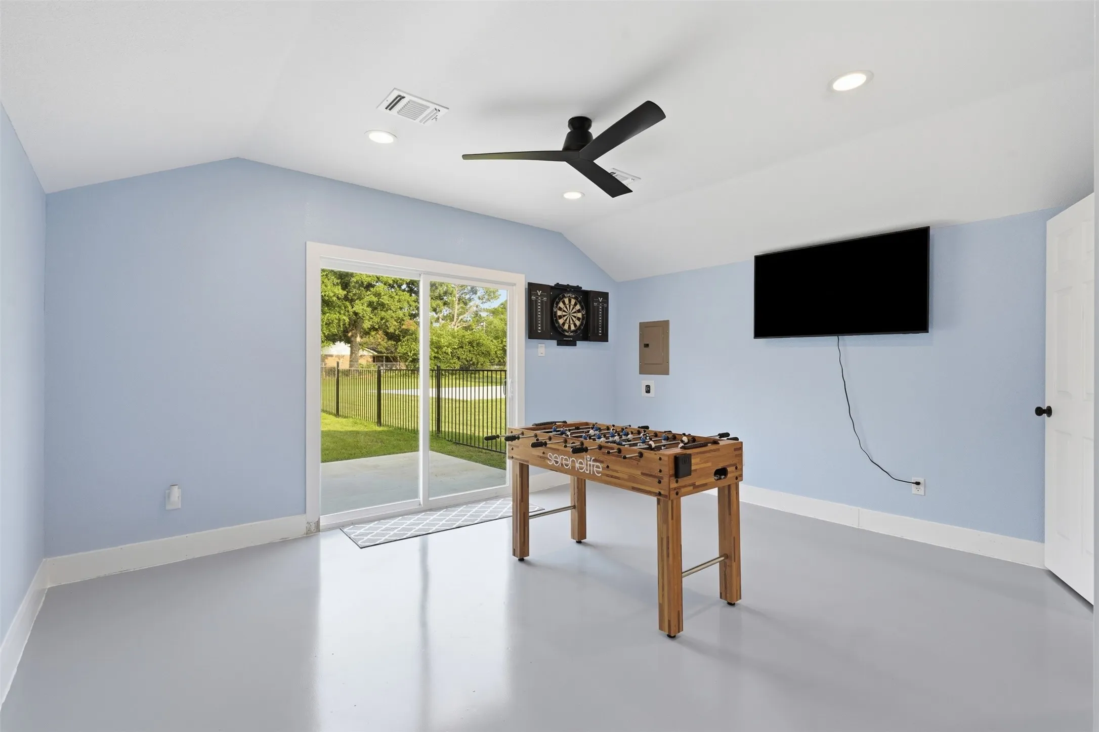 Spacious interior room featuring a vaulted ceiling and light blue walls