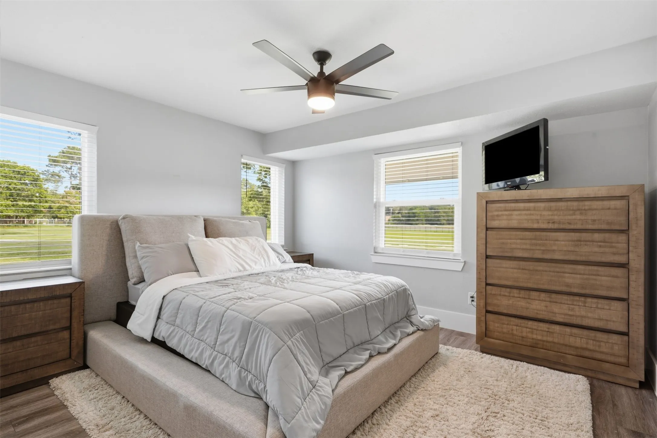 Bright bedroom featuring wood-finish flooring and light gray wall tones