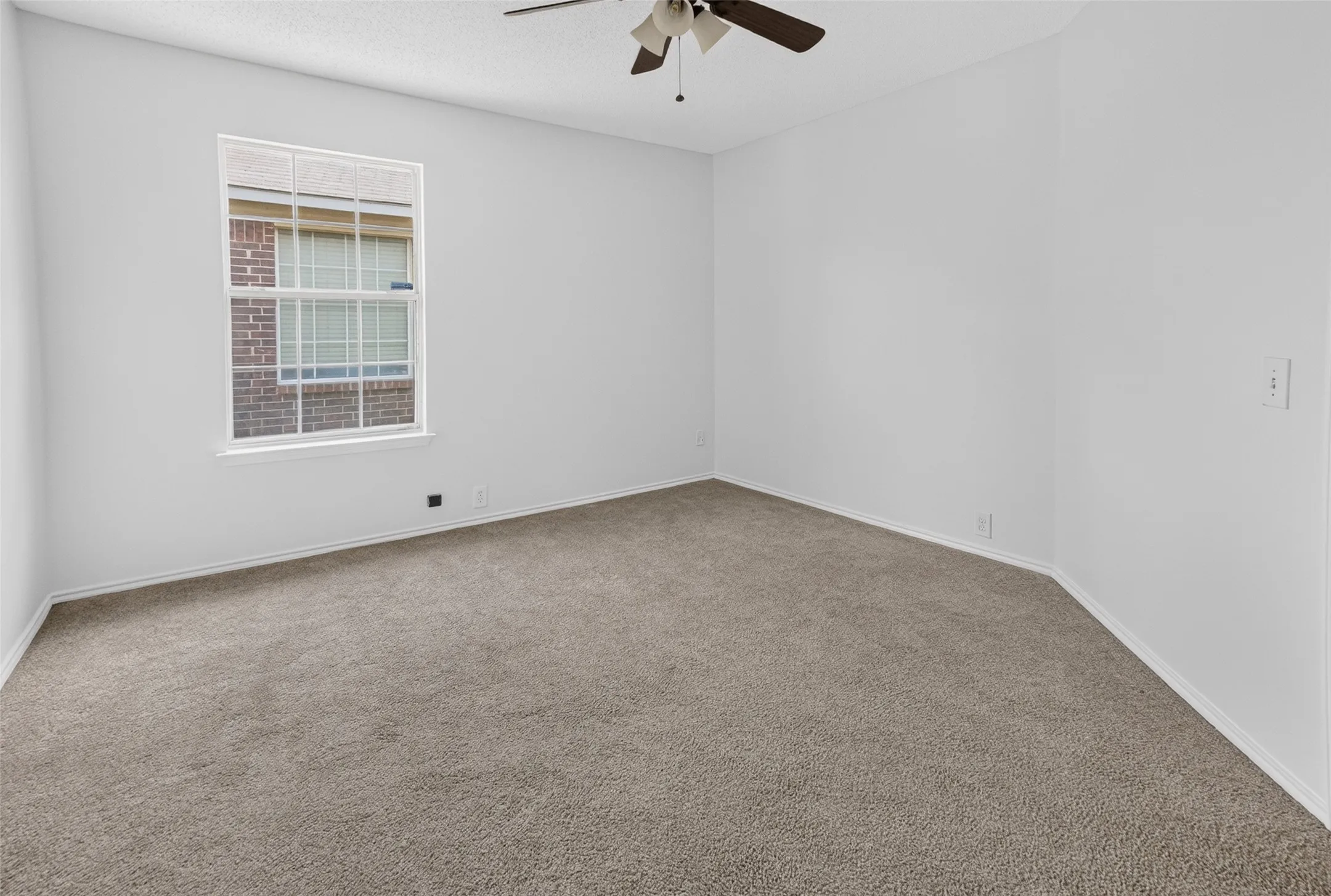 Expansive room featuring neutral-toned carpet flooring, white walls, and a multi-pane window