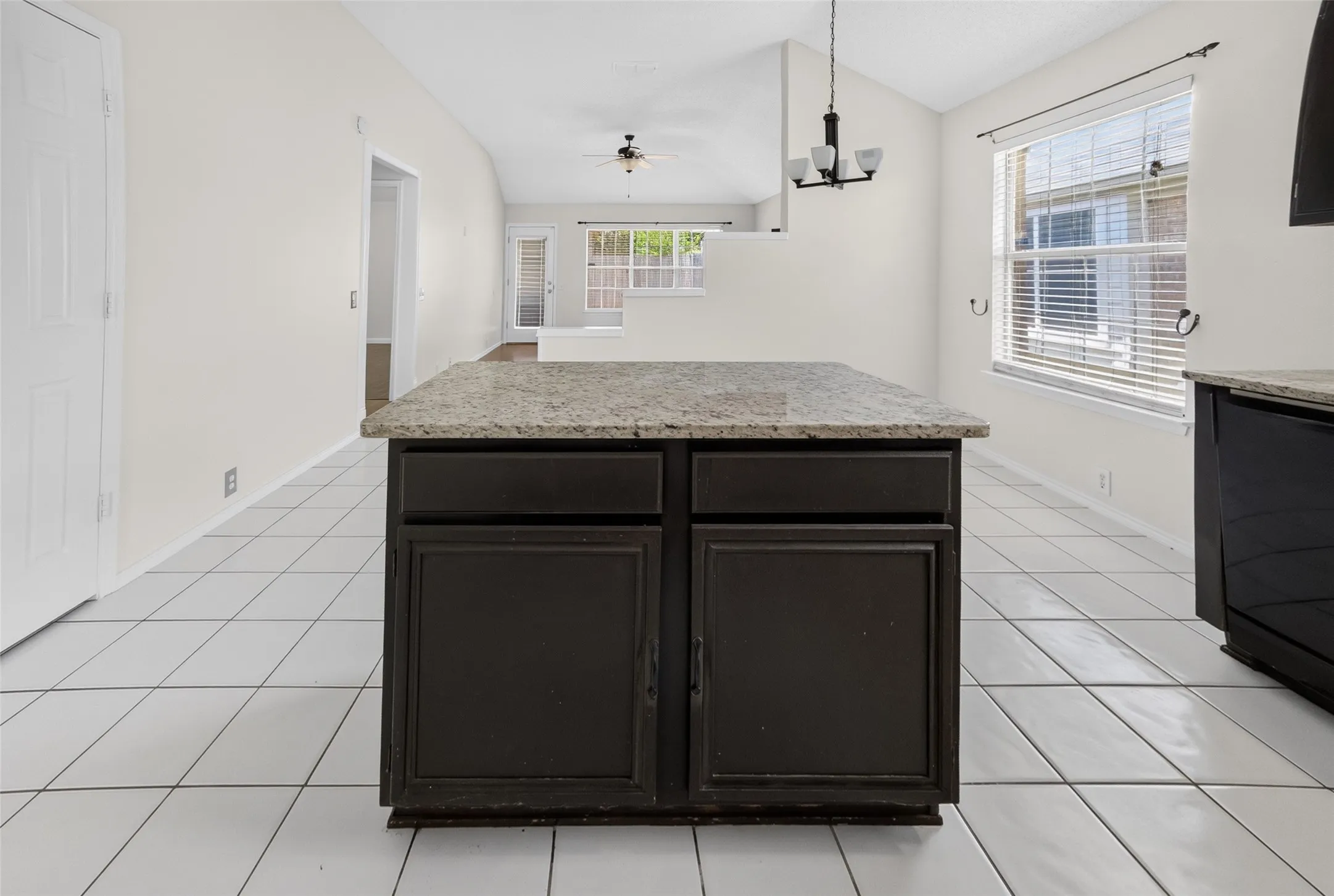 Kitchen island featuring dark wood cabinetry and a light-colored granite countertop