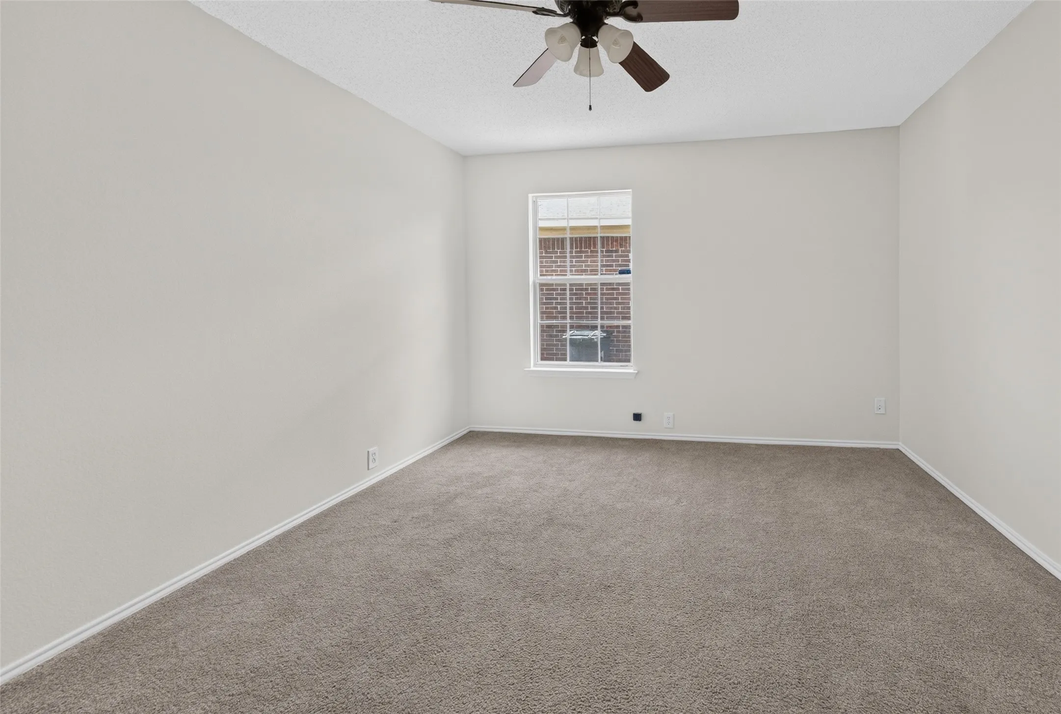 Spacious room featuring neutral carpeting, light-toned walls, and a ceiling fan with integrated lighting