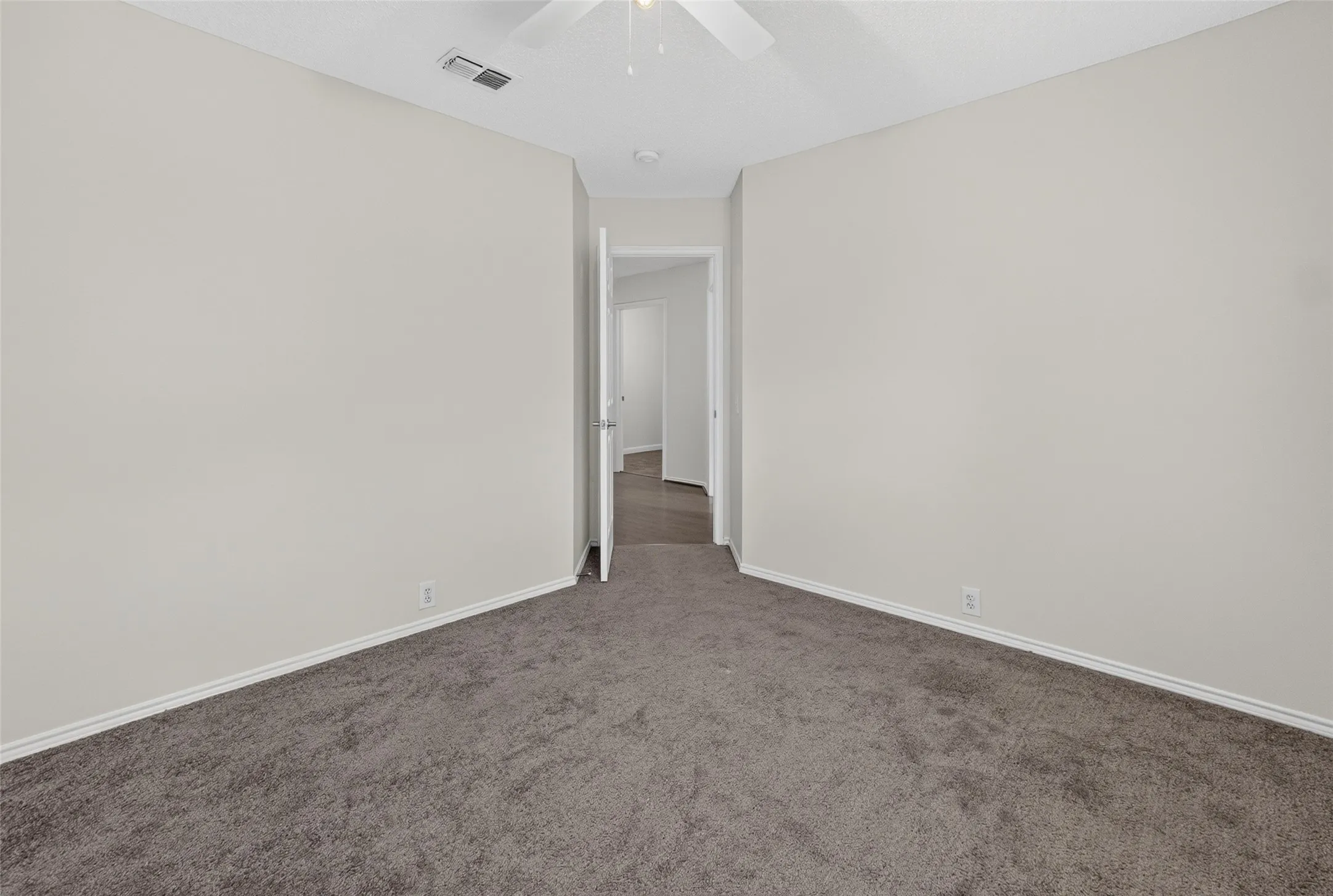 Spacious room featuring neutral carpeting, light-toned walls, and white trim