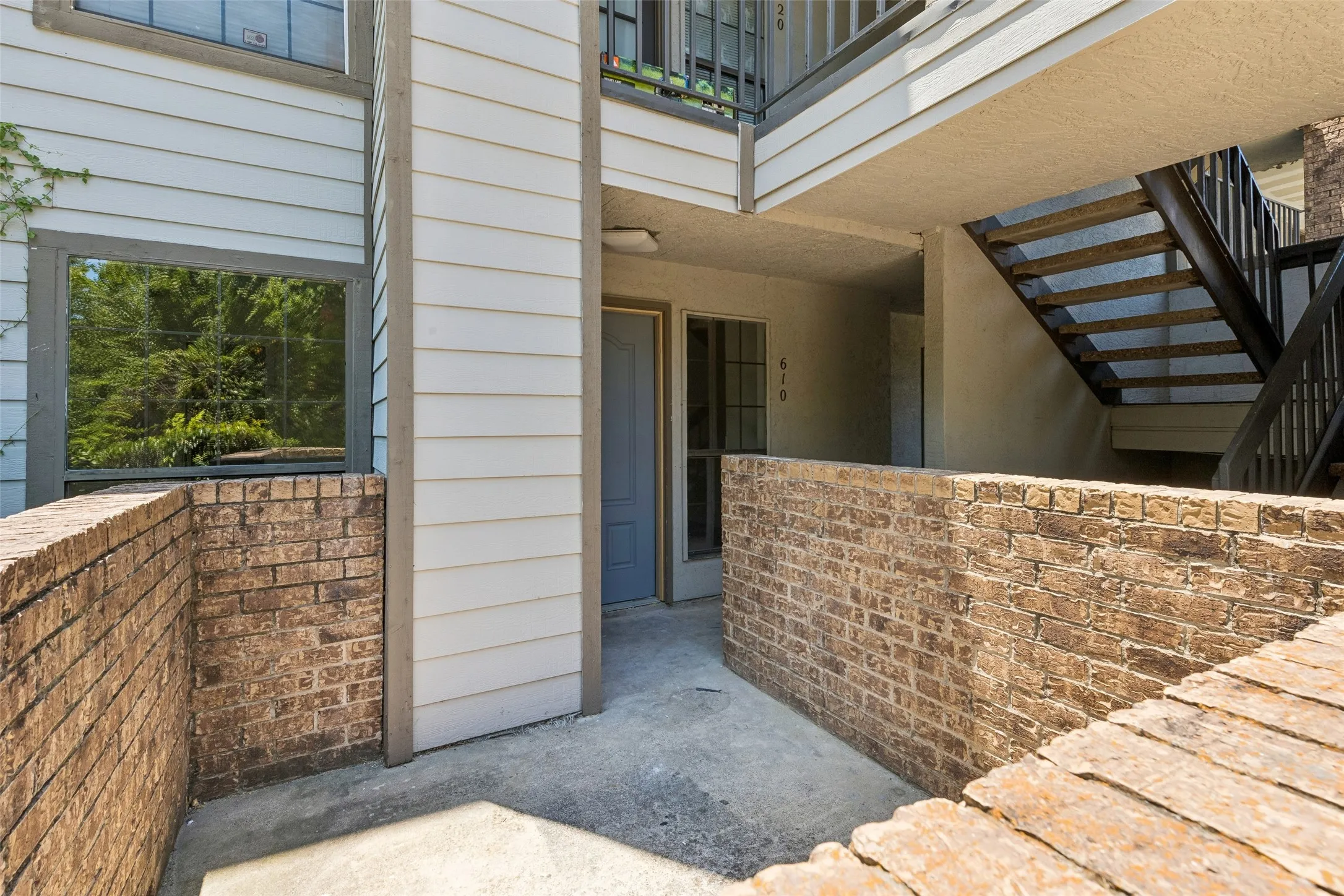 Private patio area featuring brick walls and concrete flooring