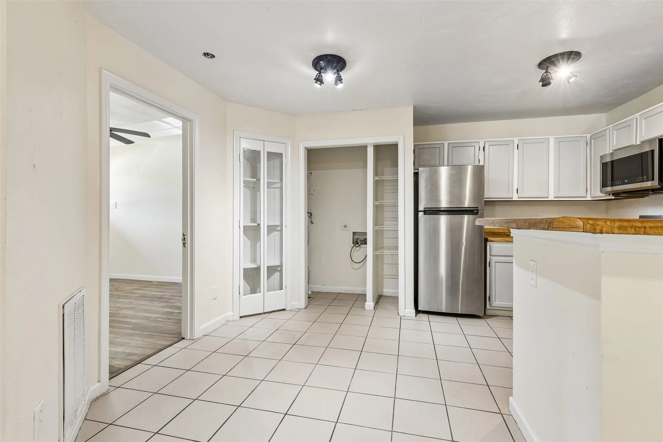 Kitchen area featuring light-toned tile flooring, light-toned cabinetry, and stainless steel appliances