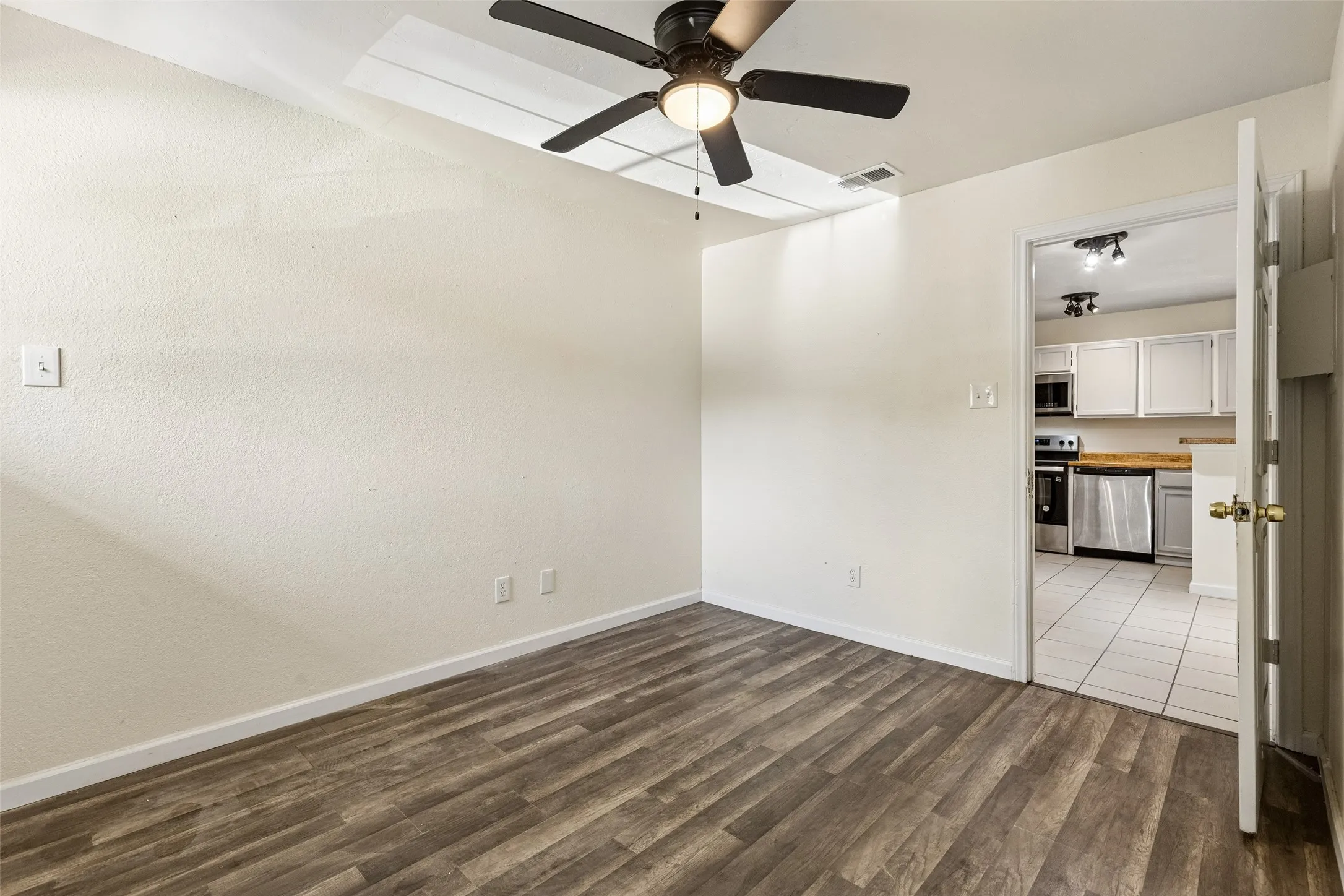 Room featuring wood-finish flooring, a ceiling fan, and white walls