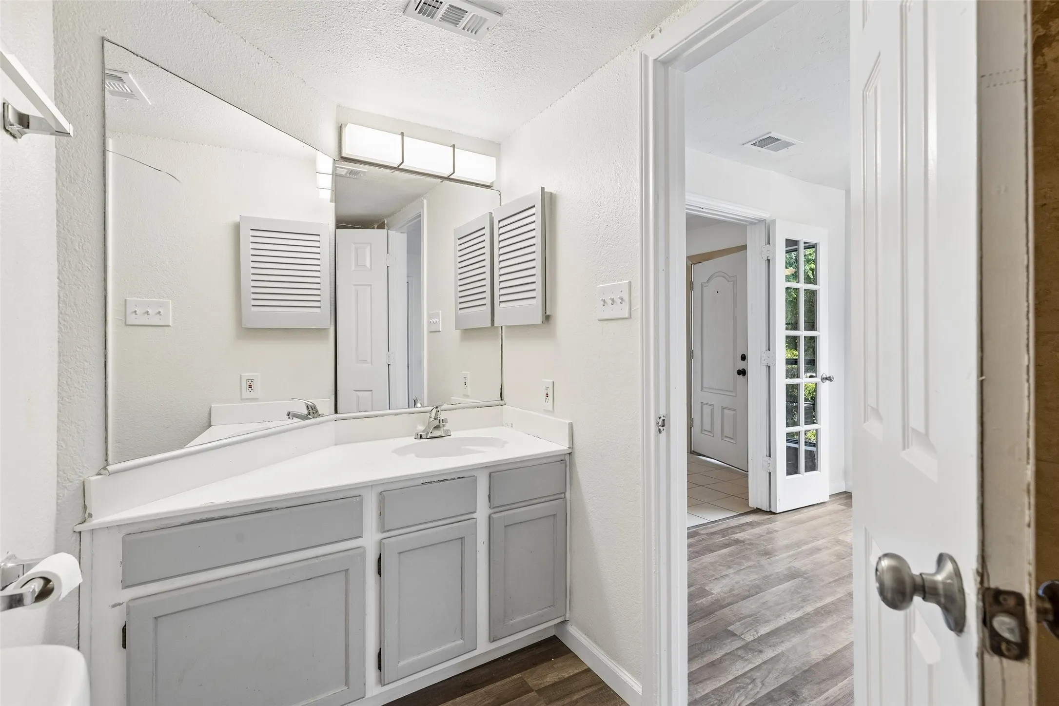 Bathroom vanity featuring a single basin sink, white countertop, and gray wood-finish cabinetry