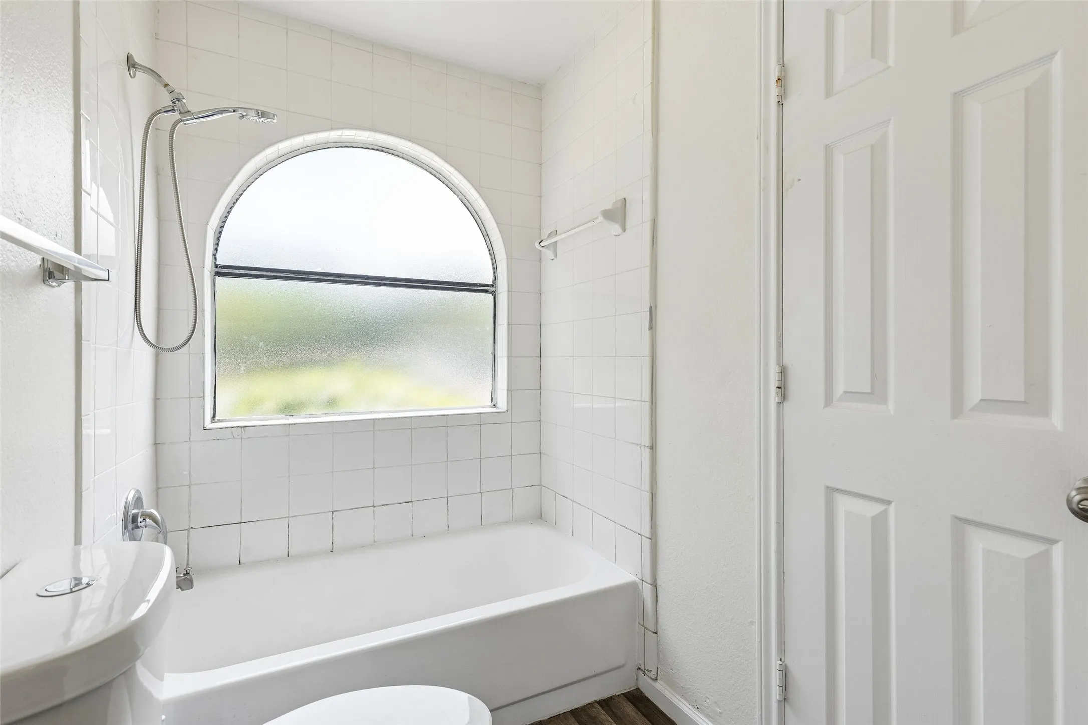 Bathroom featuring a tiled shower/tub combination with an arched privacy window
