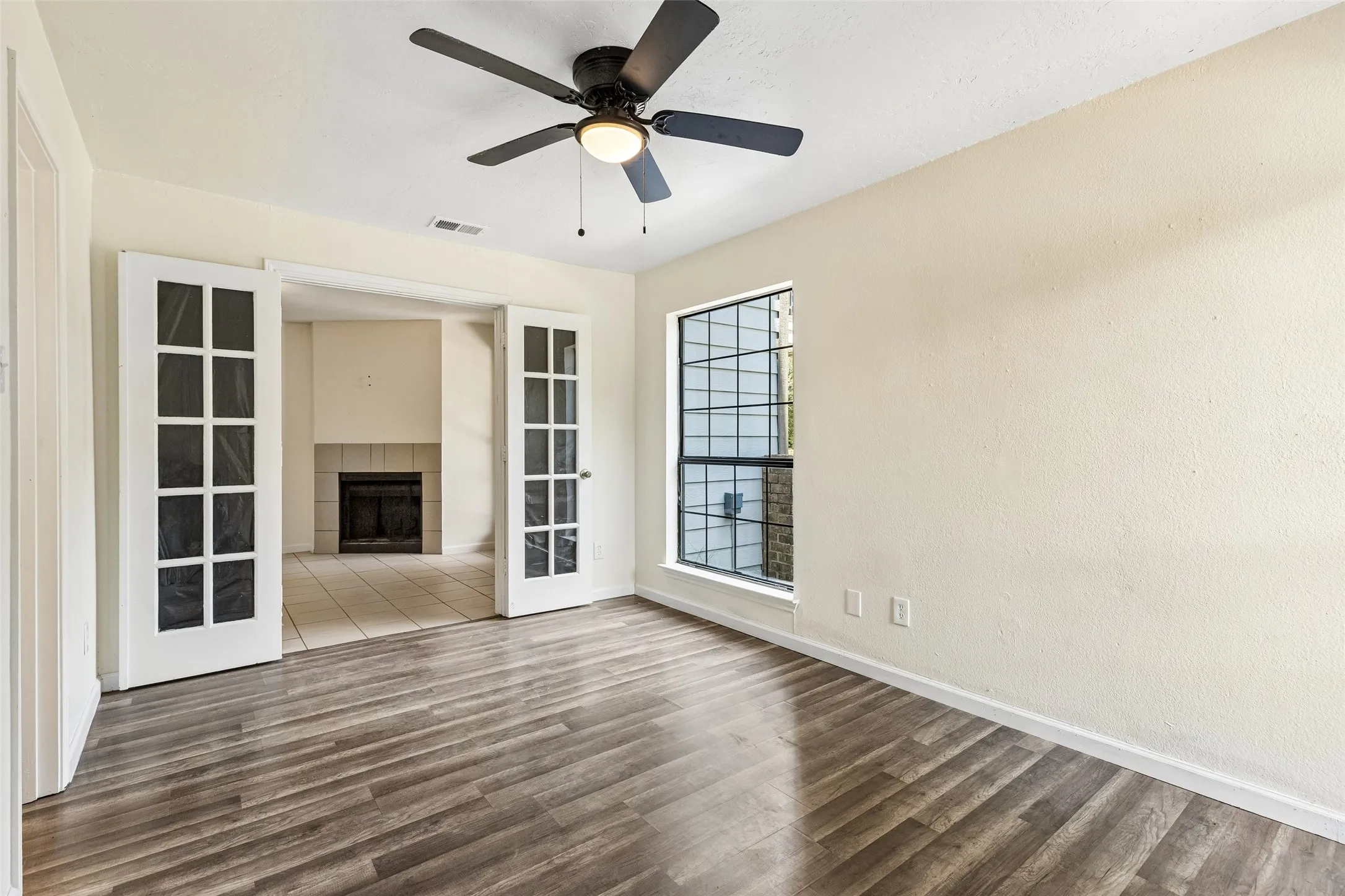 Interior room featuring wood-finish flooring, a window with grid detailing, and a ceiling fan with integrated lighting