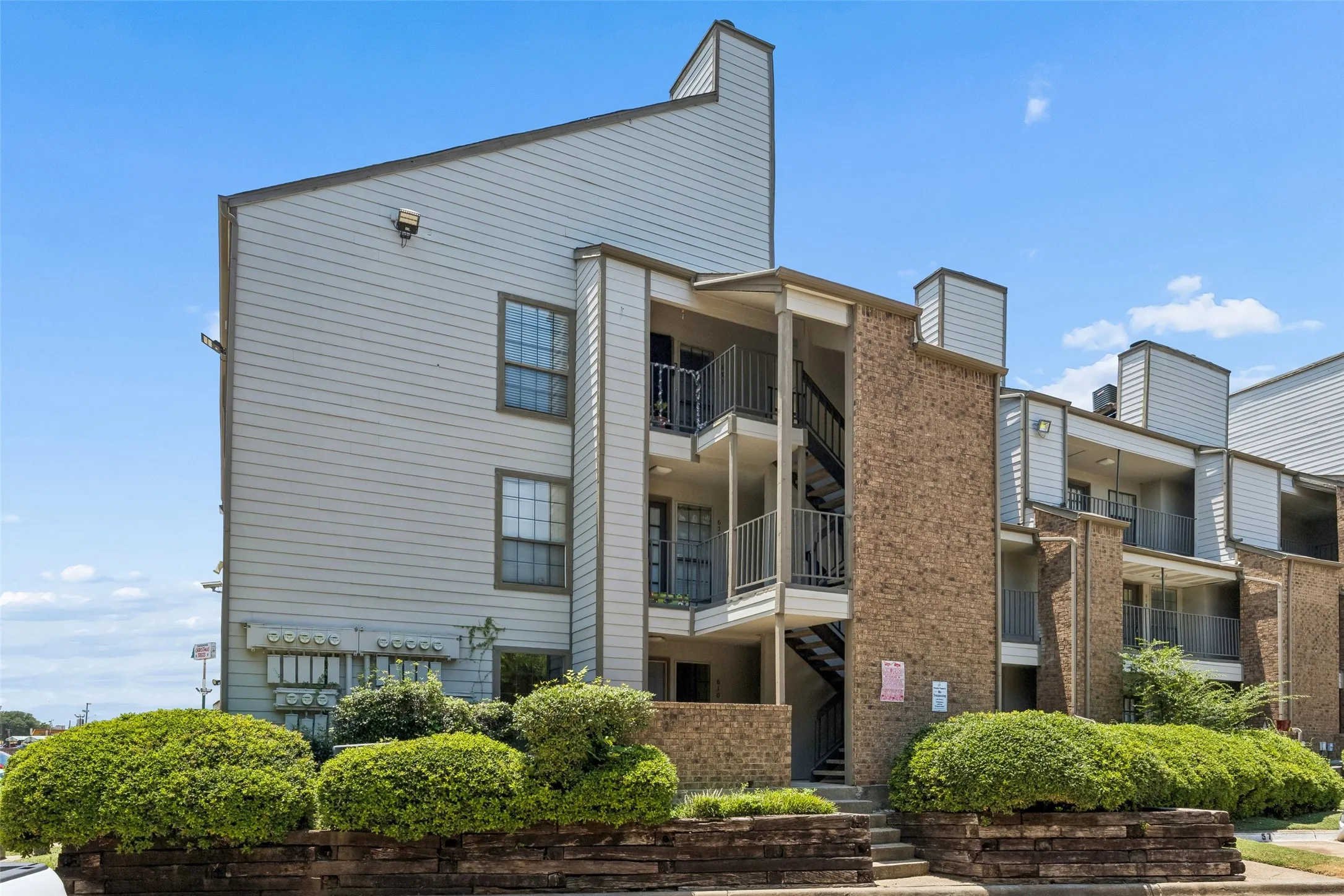 Multi-story building featuring brick and siding exteriors, private balconies with iron railings, and exterior staircases