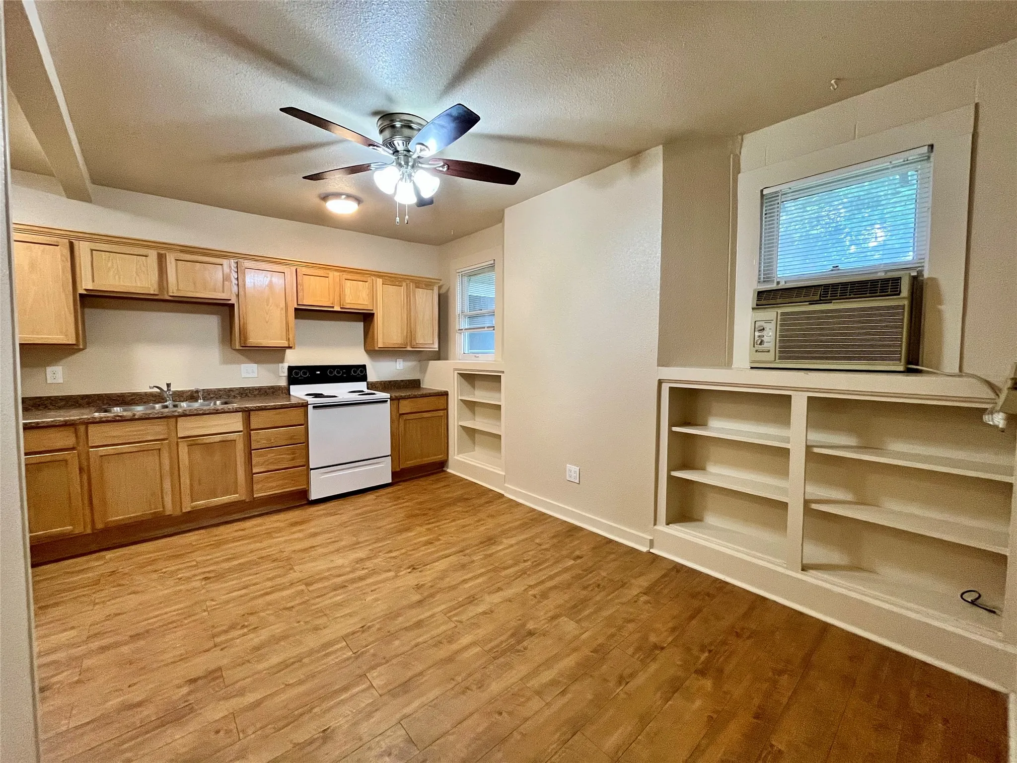 Cook and entertain with ease in this spacious kitchen featuring warm wood cabinetry, modern appliances, and a built-in bookshelf perfect for your favorite cookbooks. The open-concept design and gorgeous wood-style flooring make this the ultimate heart of the home.