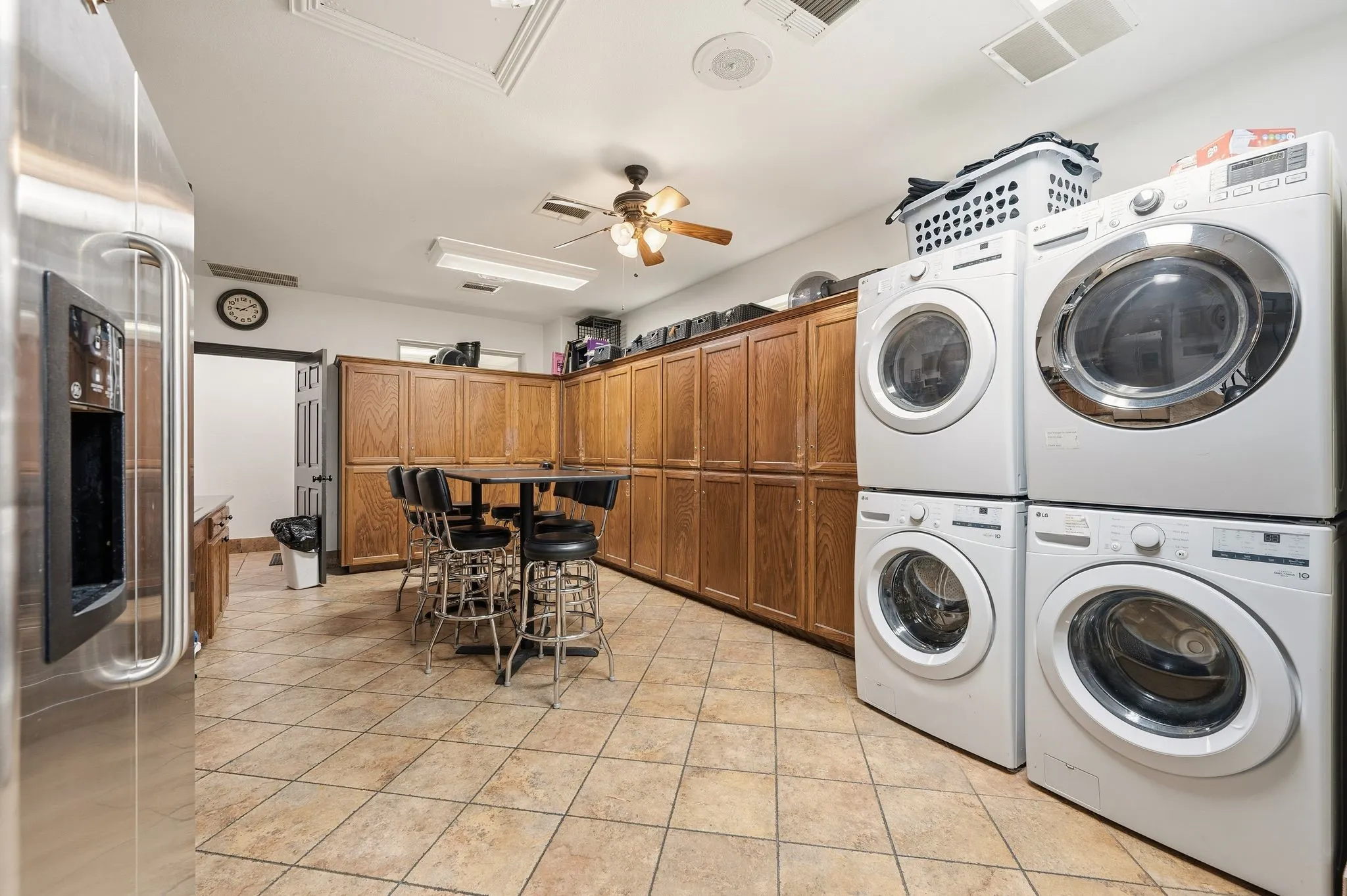 Spacious utility area featuring extensive wood cabinetry, tile flooring, and ceiling fan