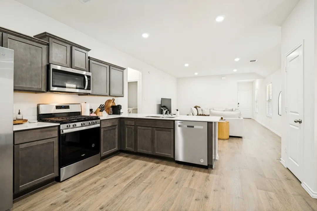 Gourmet kitchen featuring dark wood-finish cabinetry, stainless steel appliances, white countertops, and wood-finish flooring