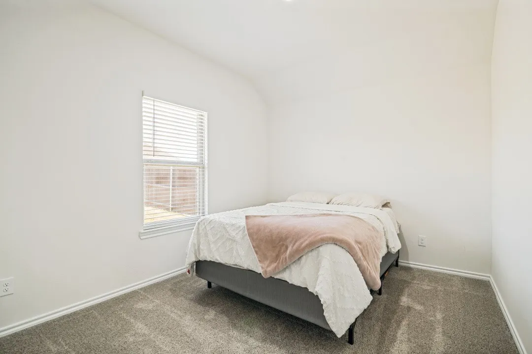 Bright room featuring neutral-toned carpeting, white walls, and a single window with horizontal blinds