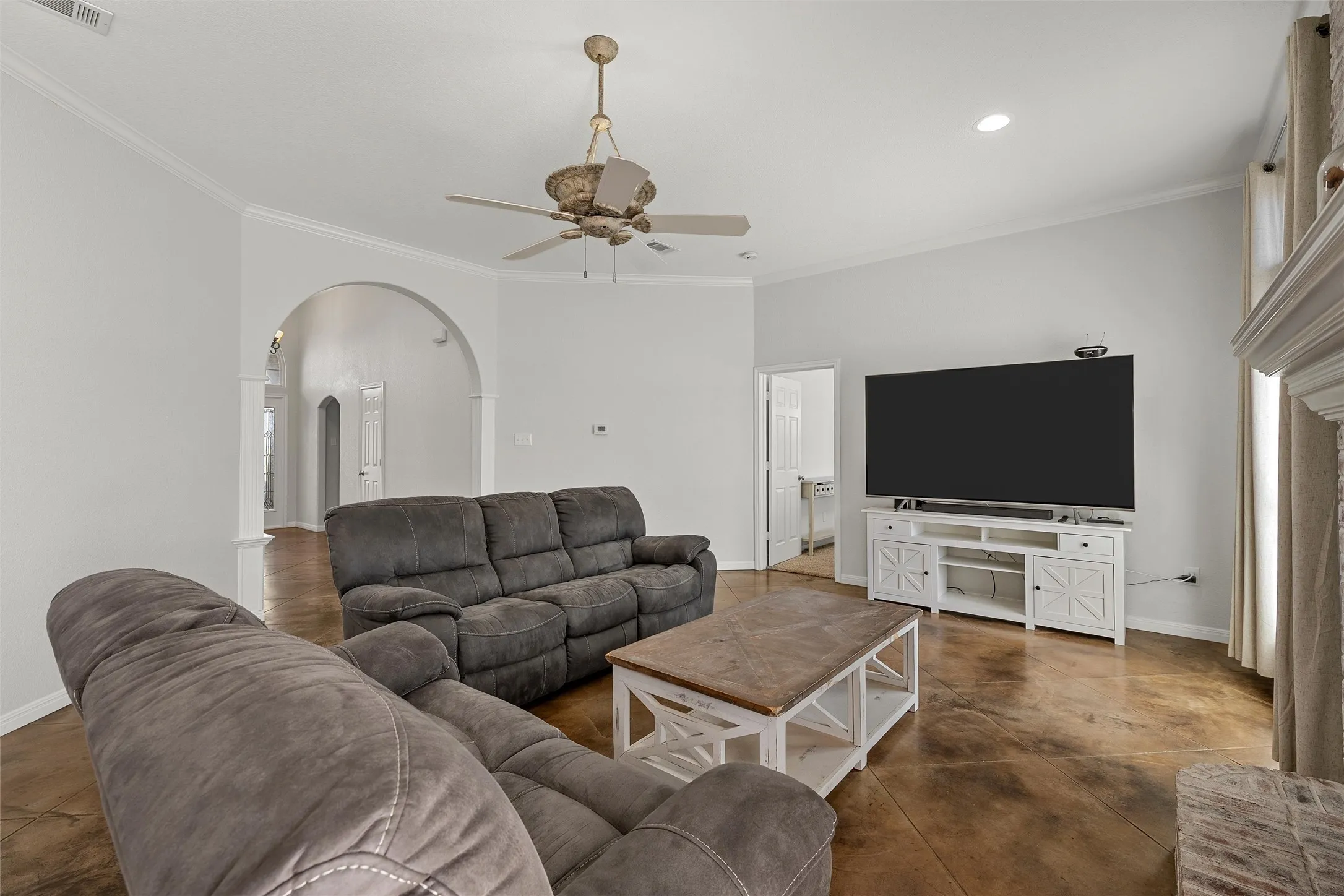 Living area featuring warm-toned concrete flooring, vaulted ceiling, and crown molding