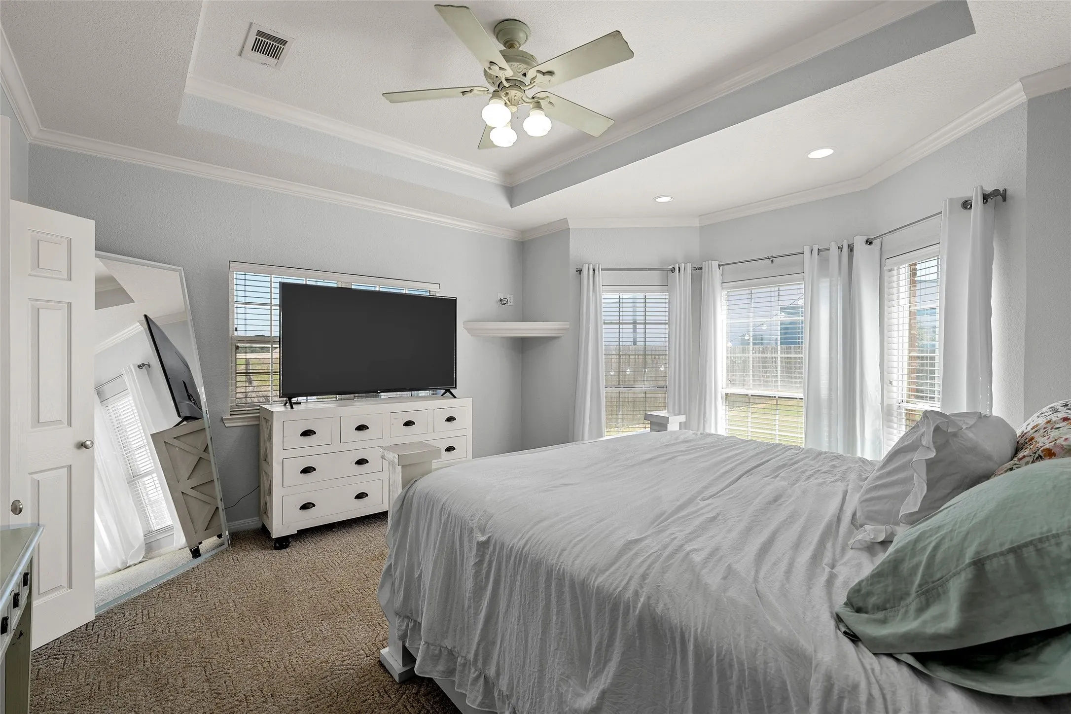Spacious room featuring a tray ceiling, recessed lighting, and a ceiling fan