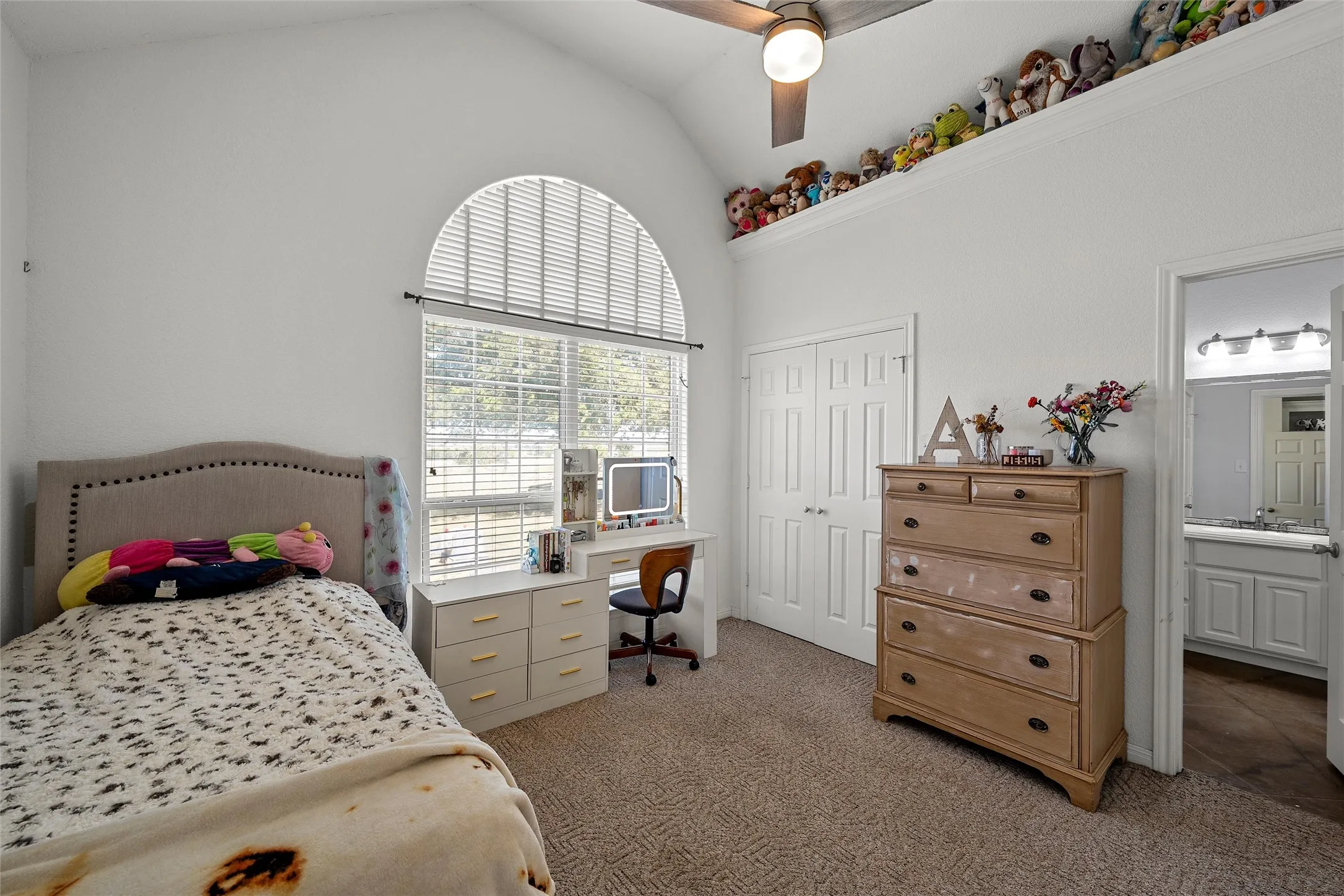 Arched window with blinds, vaulted ceiling, and ceiling fan