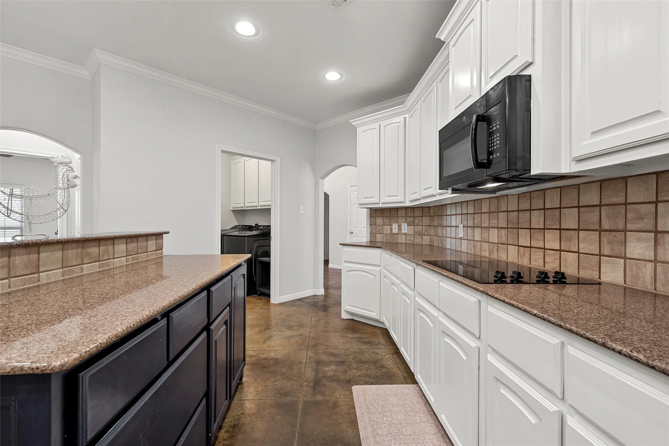 Kitchen featuring white cabinetry, a built-in microwave, a flat-top electric range, and a tile backsplash