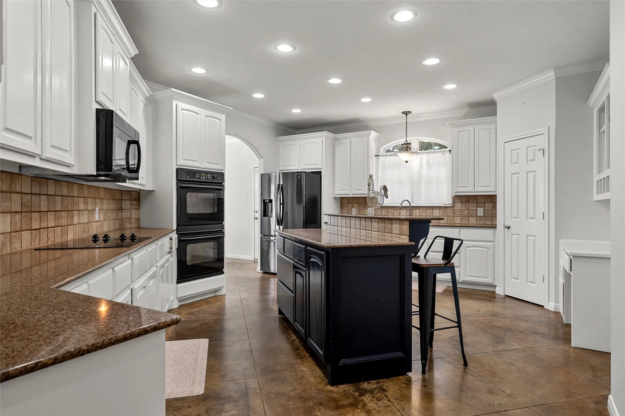 Spacious kitchen featuring white cabinetry, brown granite-finish countertops, and a tiled backsplash
