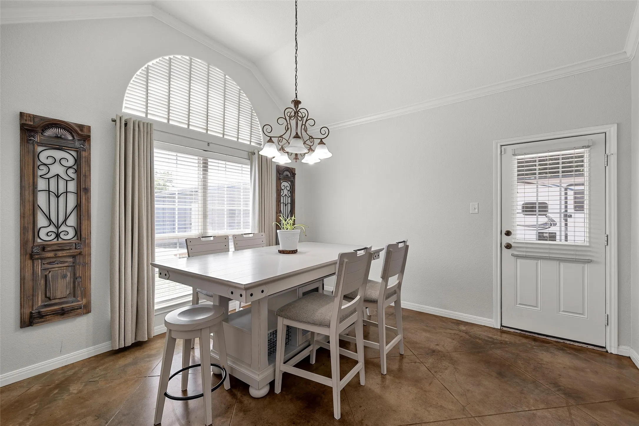 Spacious living area featuring polished concrete flooring, arched doorways, a brick fireplace with a white mantel, recessed lighting, and crown molding