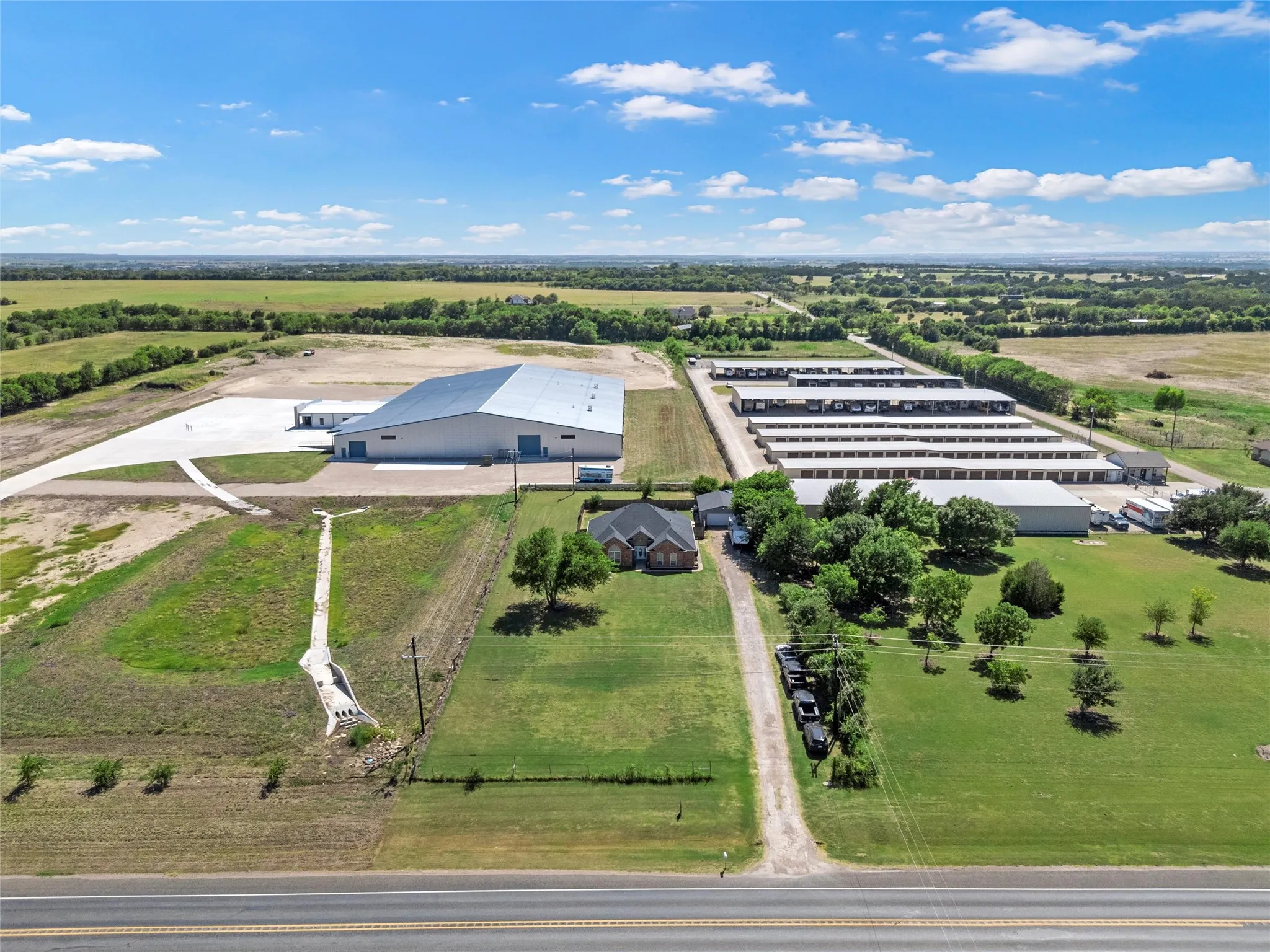 Expansive property featuring multiple structures including a large warehouse, extensive storage units, and a brick-built residential structure