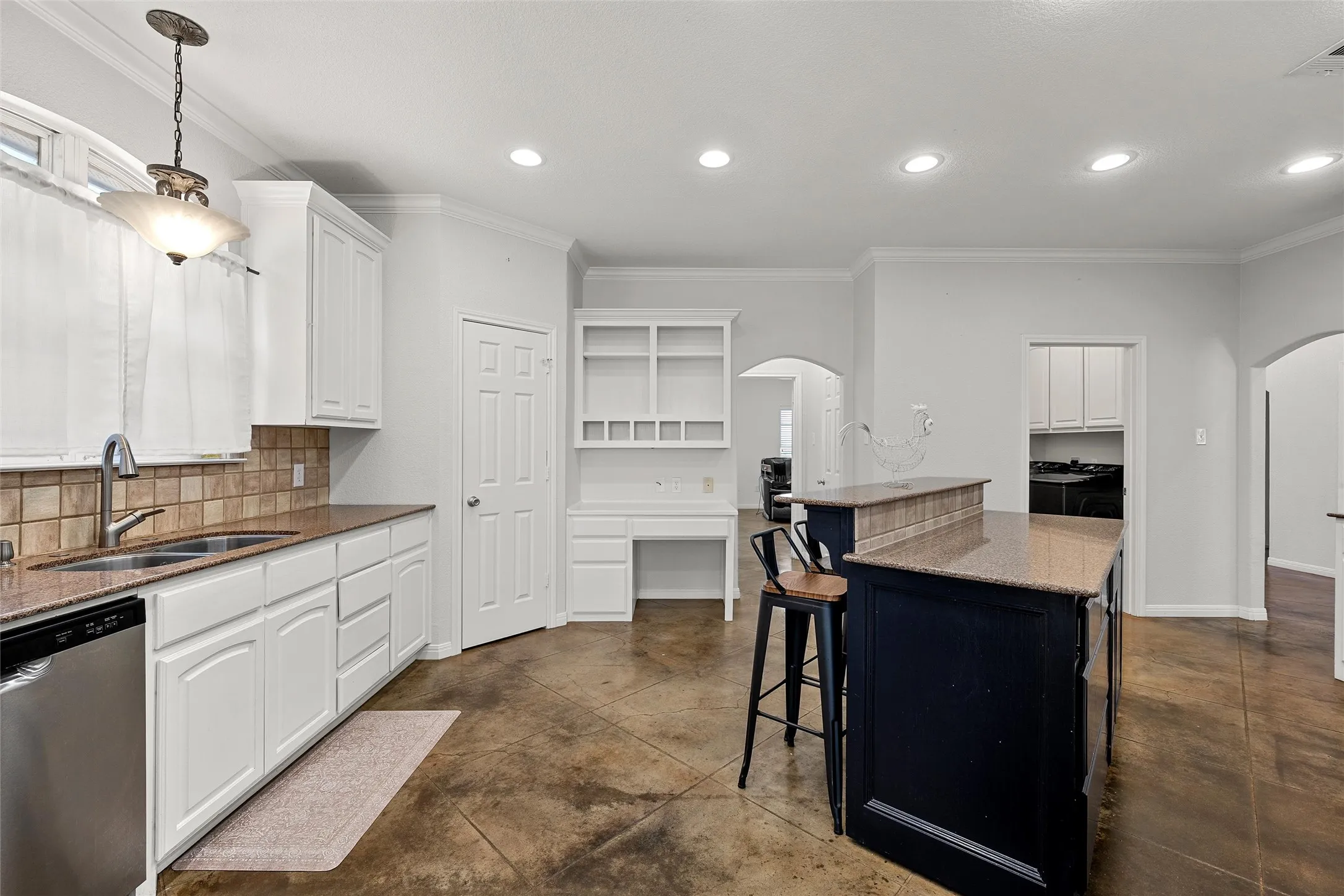 Kitchen featuring white cabinetry, granite countertops, tile backsplash, stainless steel dishwasher, and a center island with a built-in breakfast bar