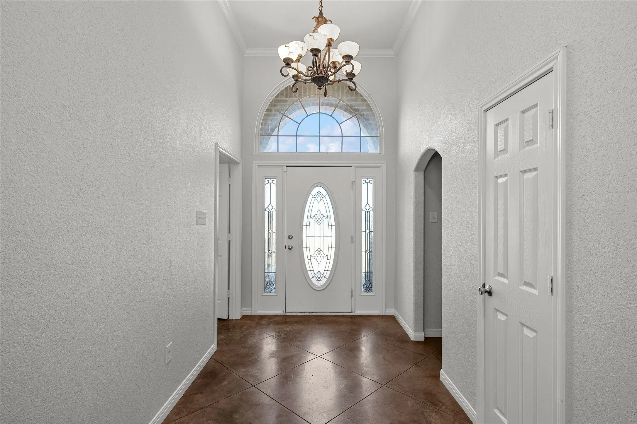 Grand entryway featuring a decorative glass front door, transom window, and sidelights