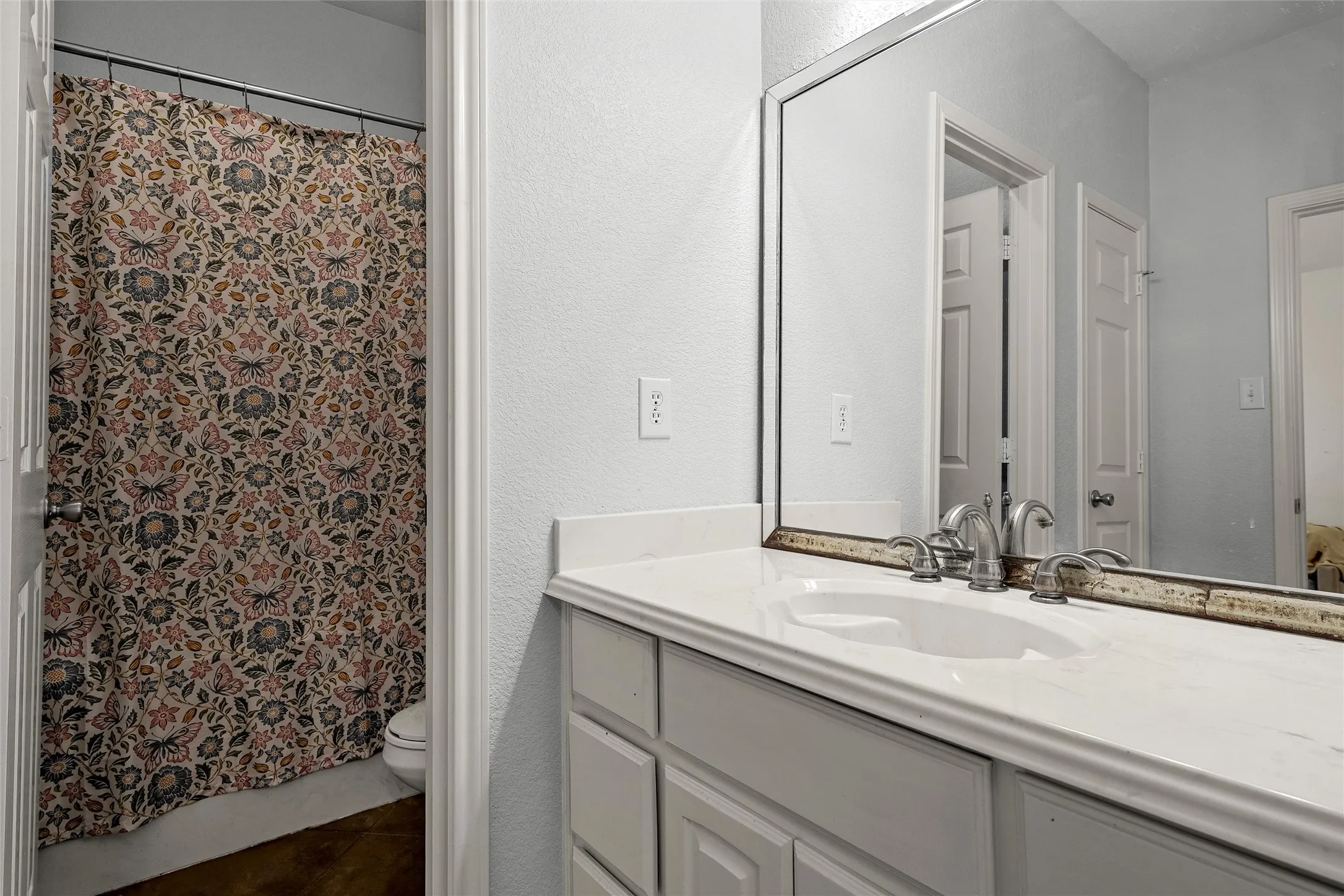 Bathroom vanity featuring a white countertop with integrated sink, brushed nickel faucet, and a framed mirror