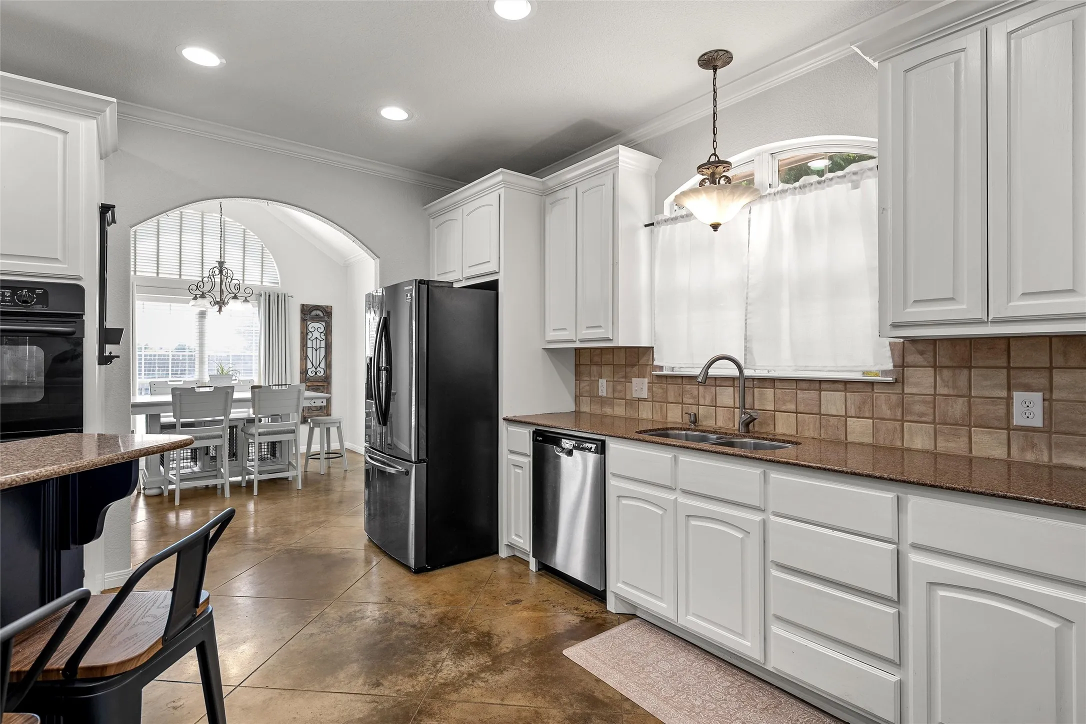 Kitchen featuring white cabinetry, a double basin sink with a gooseneck faucet, light brown countertops, and a tiled backsplash