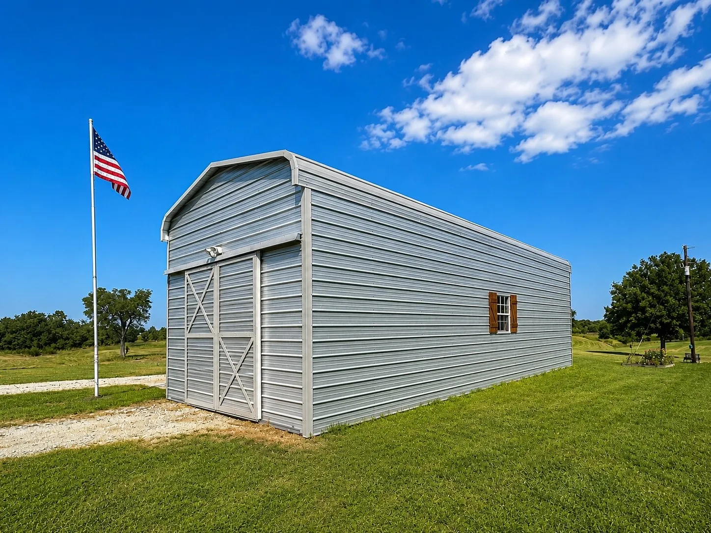 Corrugated metal outbuilding featuring a barn-style sliding door, an exterior light fixture, and a single window with brown shutters
