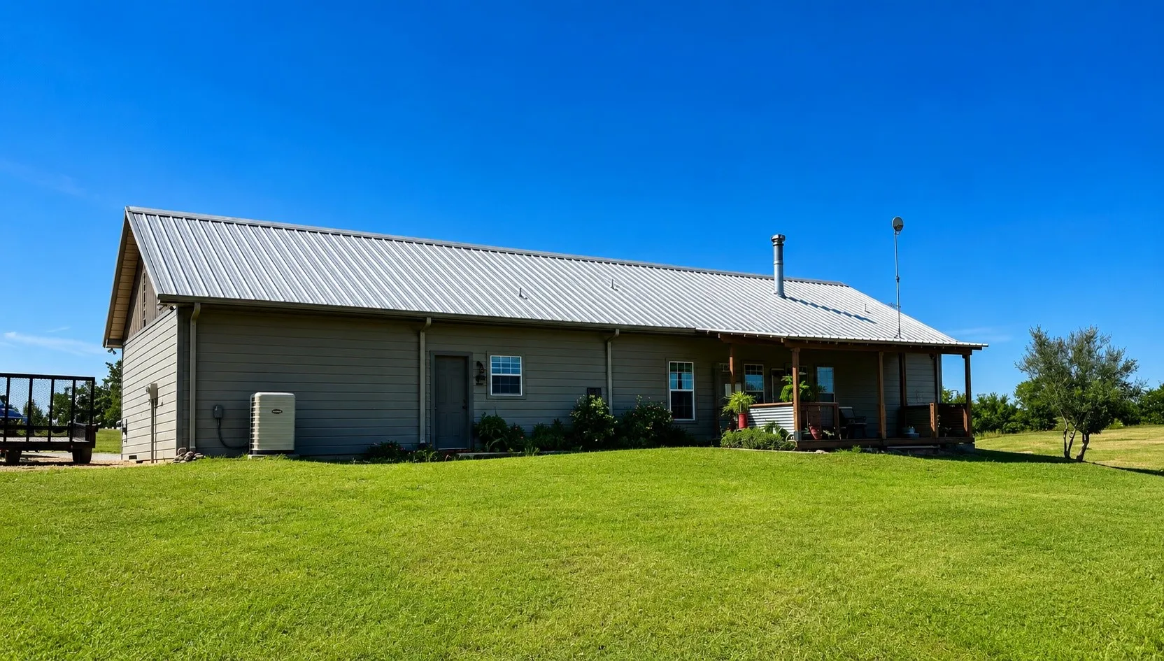 Single-story dwelling featuring a metal roof, neutral-toned siding, and a covered rear porch with wood columns