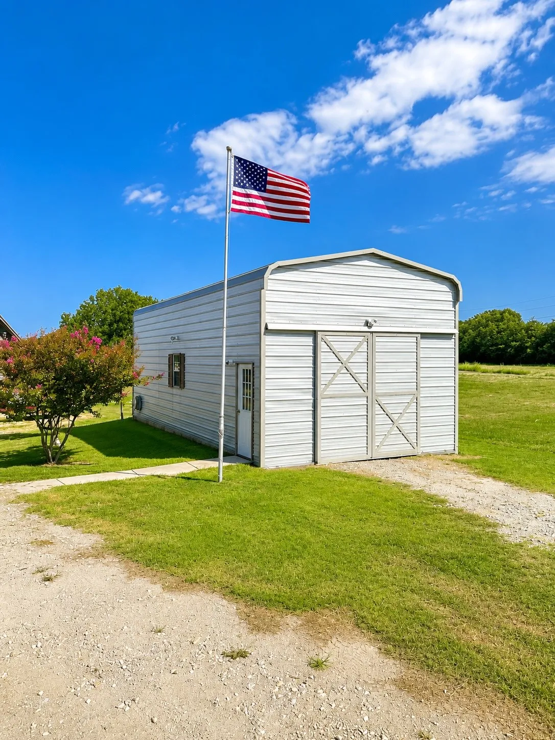Corrugated metal outbuilding featuring a barn-style sliding door, an exterior light fixture, and a single window with brown shutters