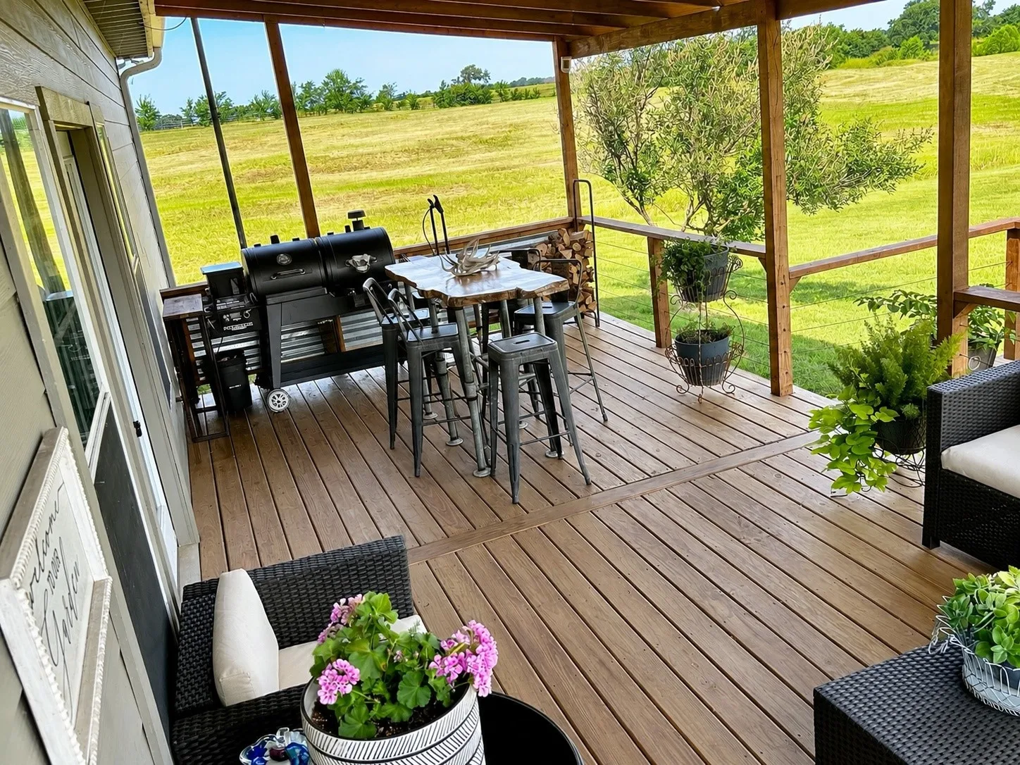 Spacious covered deck featuring wood-finish flooring, exposed timber beams, and a wood railing