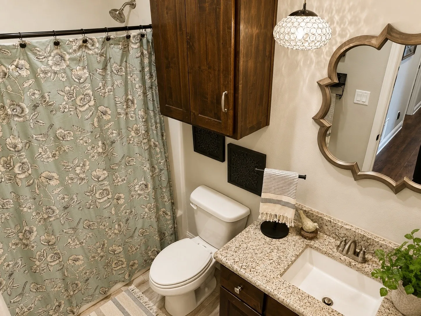 Bathroom featuring a granite countertop vanity with an undermount sink, a decorative framed mirror, and a wall-mounted wood-finish cabinet