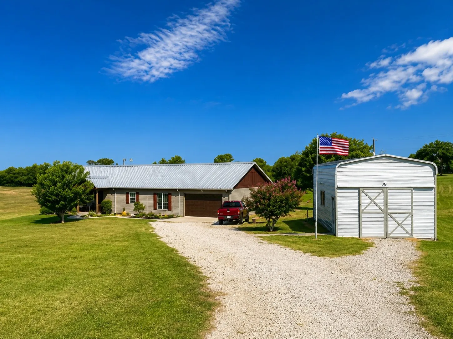Single-story residence featuring a metal roof, attached garage, and a gravel driveway