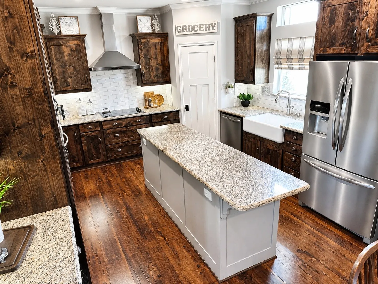 Kitchen featuring dark wood-finish cabinetry, white subway tile backsplash, and light-toned stone countertops