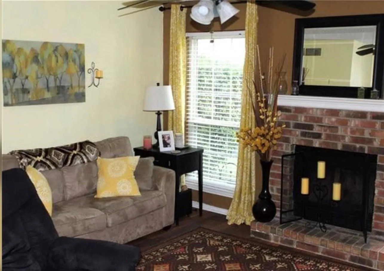 Brick fireplace with a white mantel and a black framed mirror