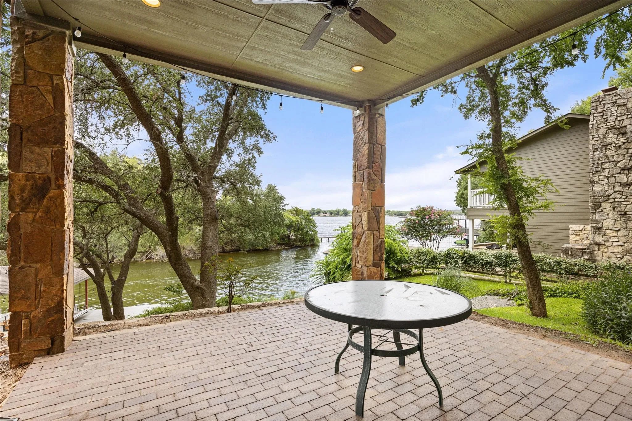 Covered outdoor patio featuring stone columns and a brick paver surface