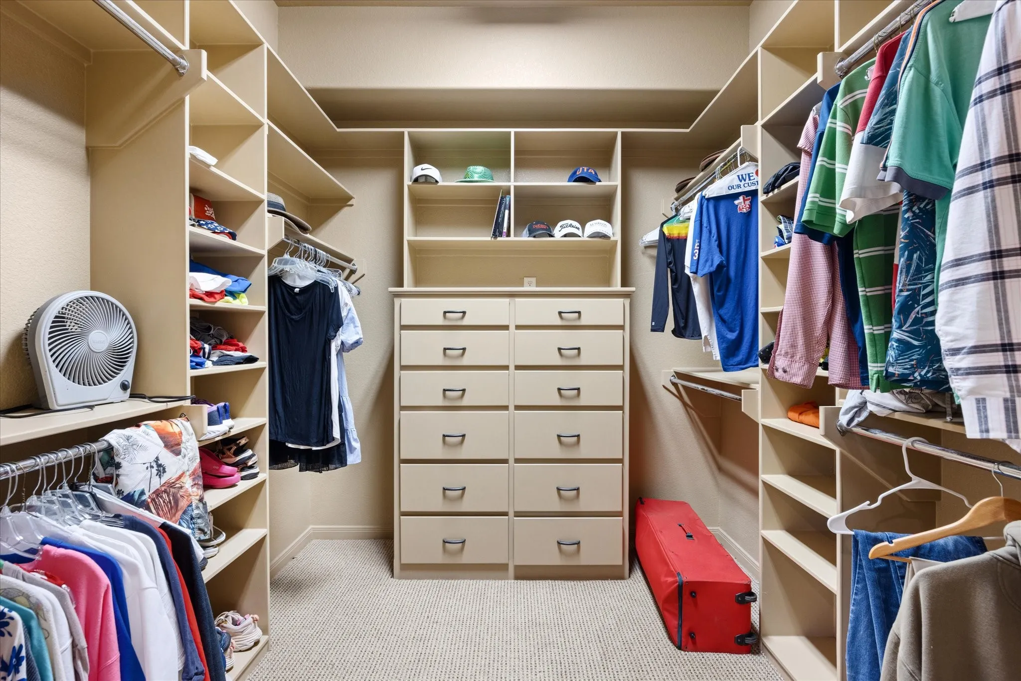 Custom closet system featuring built-in shelving, multiple hanging rods, and a central dresser unit with drawers