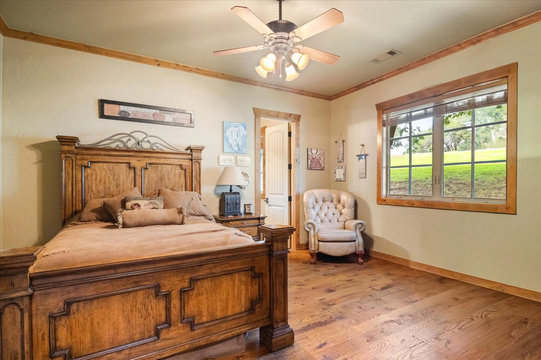 Spacious room featuring wood-finish flooring, wood trim, a ceiling fan with integrated lighting, and a large window with natural light