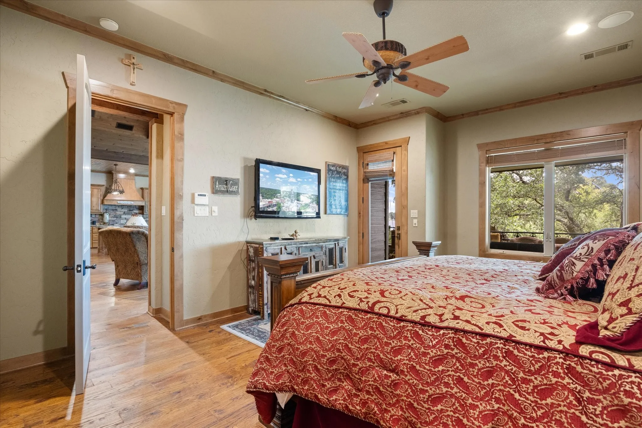Spacious room featuring wood-finish flooring, a ceiling fan, large windows, and natural wood trim throughout
