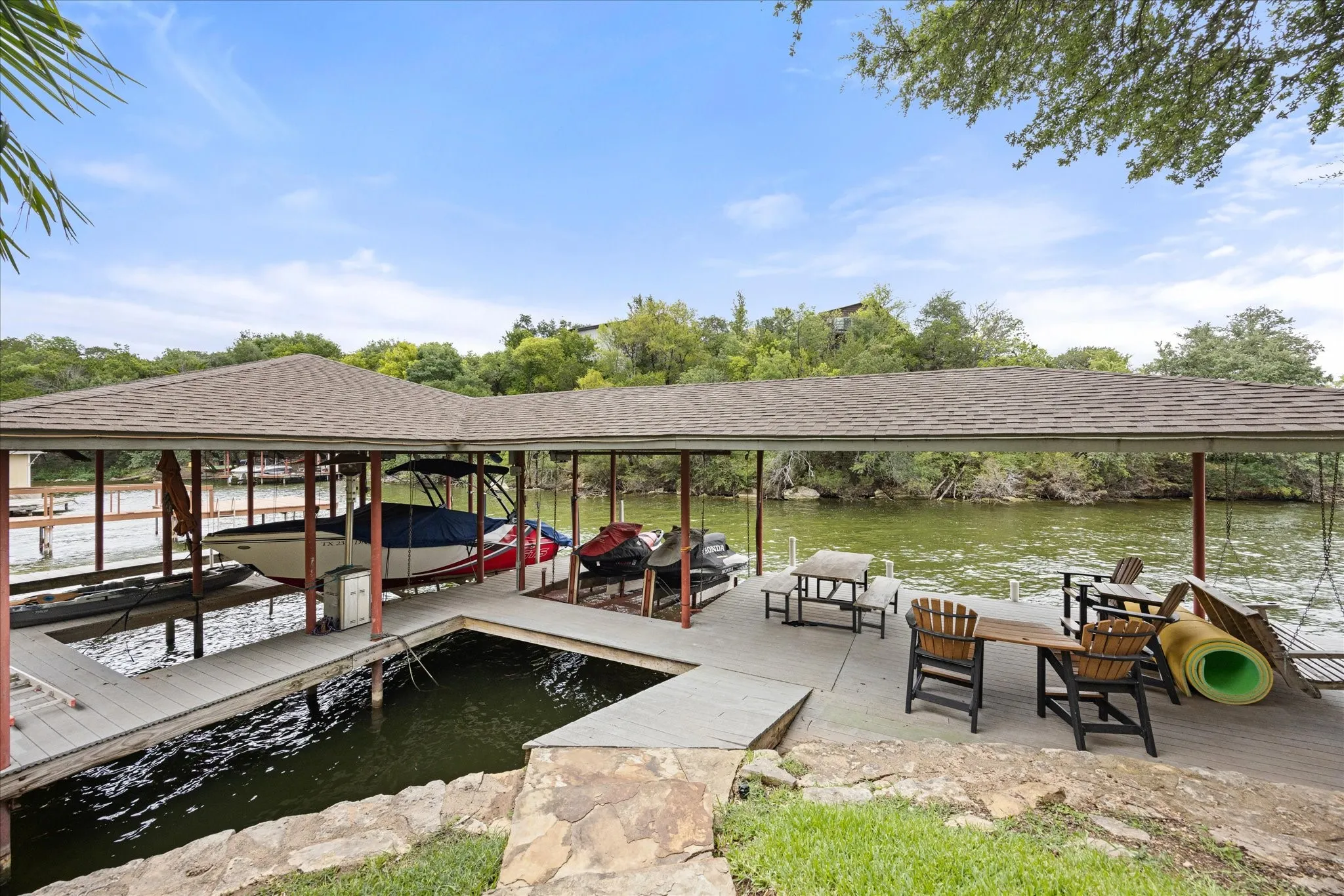 Covered boat dock featuring two boat slips and a spacious waterfront deck