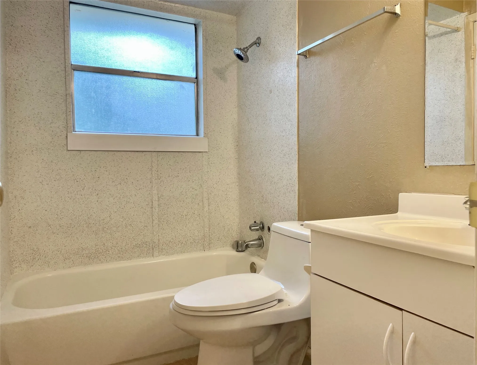 Full bathroom with  shower combination, vanity, and a textured wall