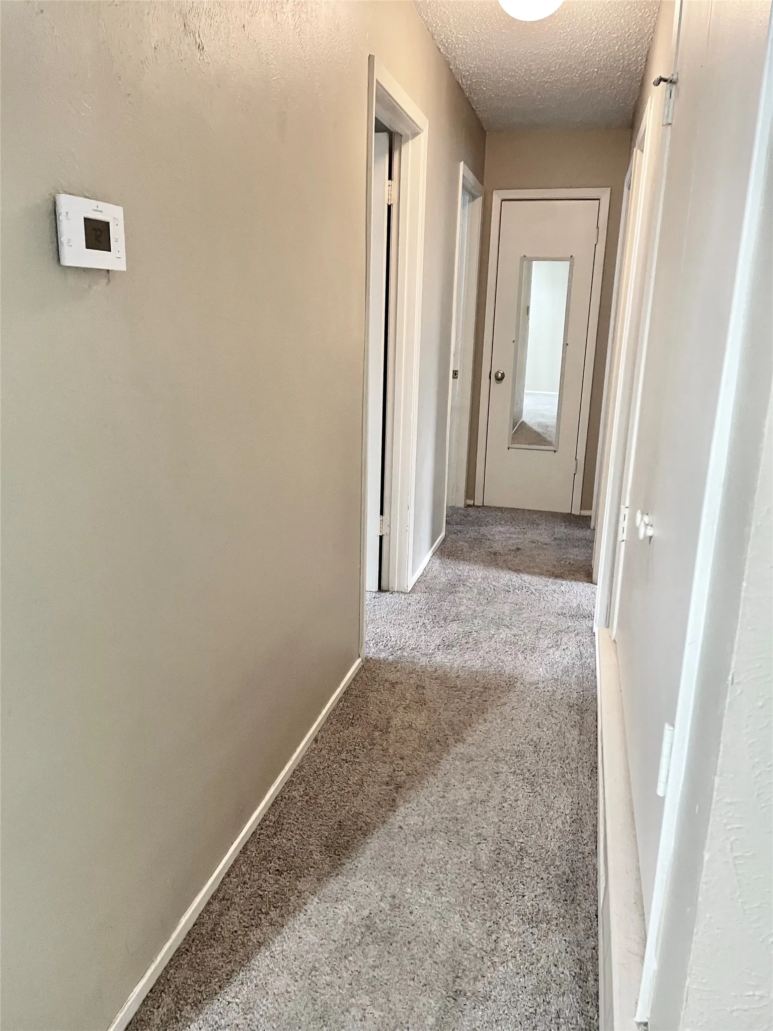 Hall featuring a textured ceiling and carpet floors