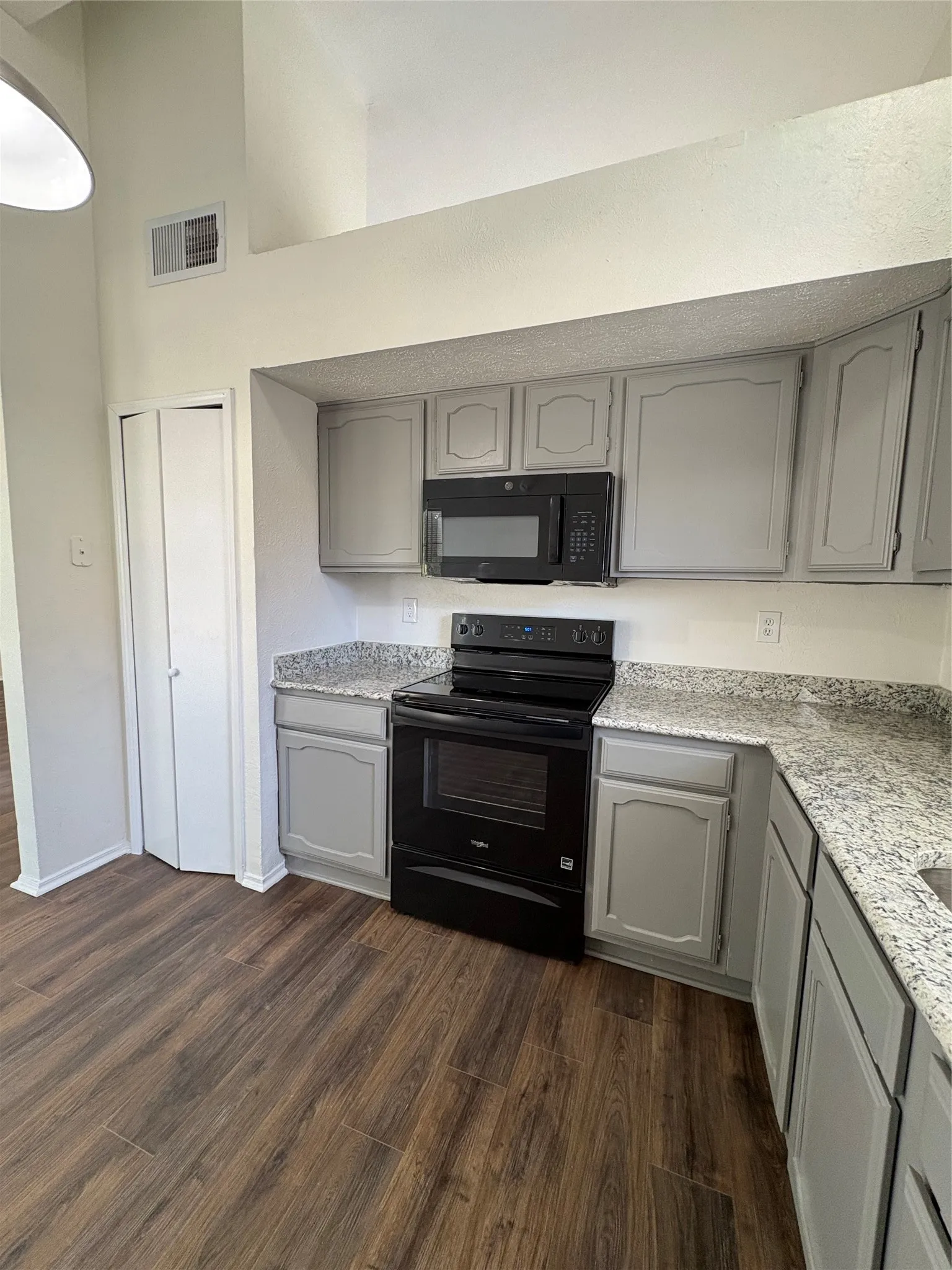 Kitchen featuring light gray cabinetry, granite-finish countertops, and wood-finish flooring